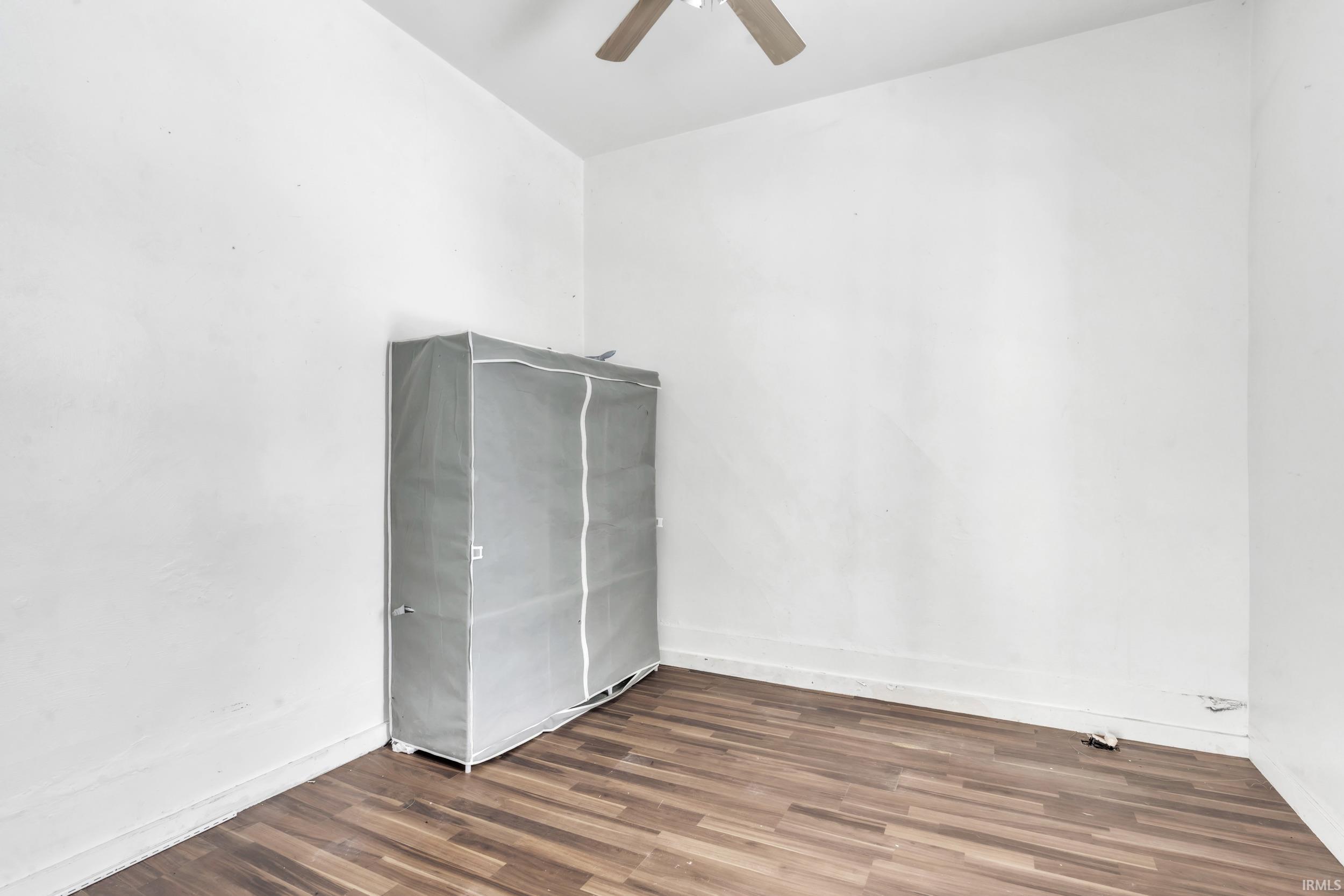 Unfurnished room featuring dark wood-style flooring and ceiling fan