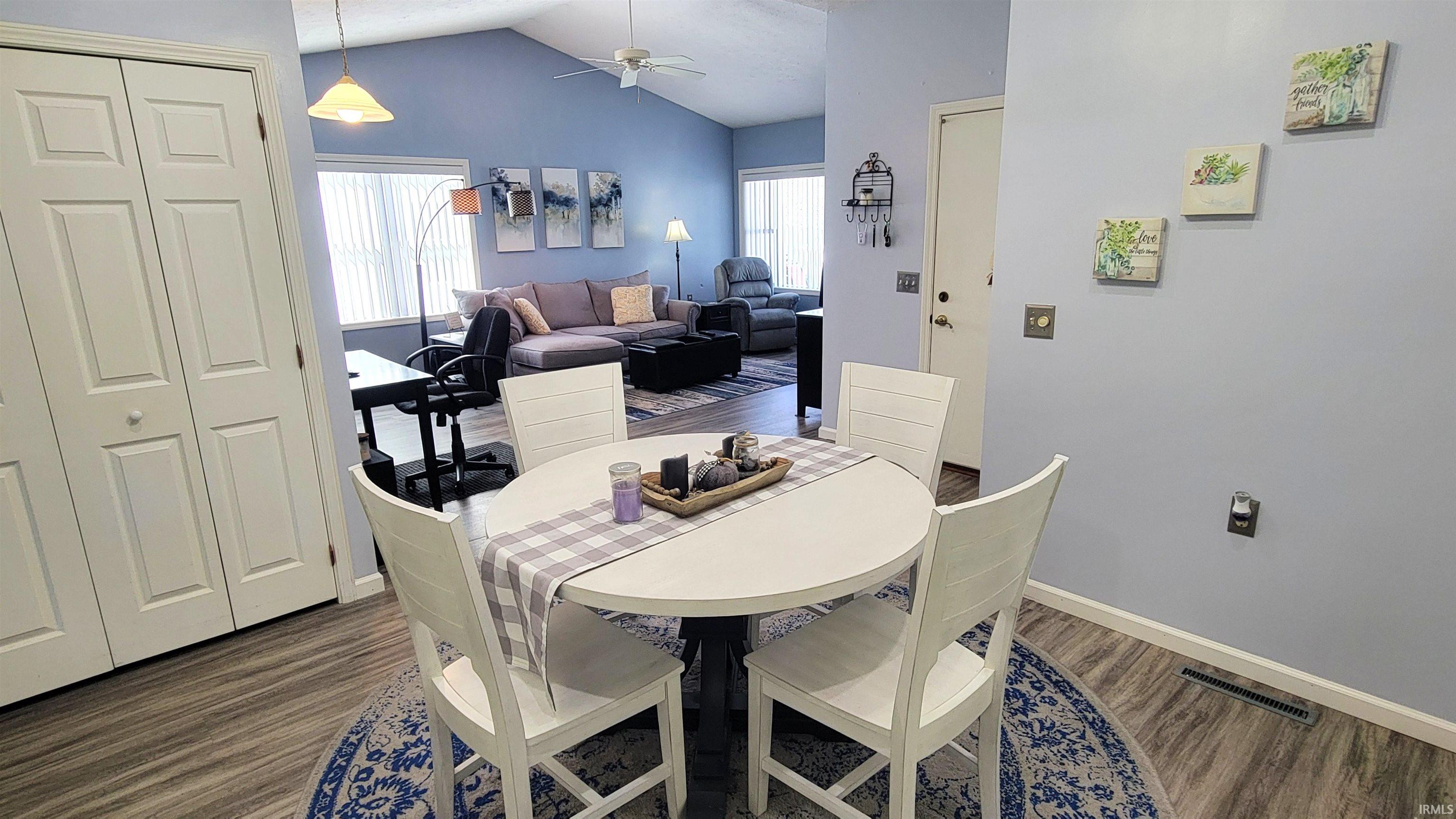 Dining space featuring dark wood-style floors, lofted ceiling, and a ceiling fan