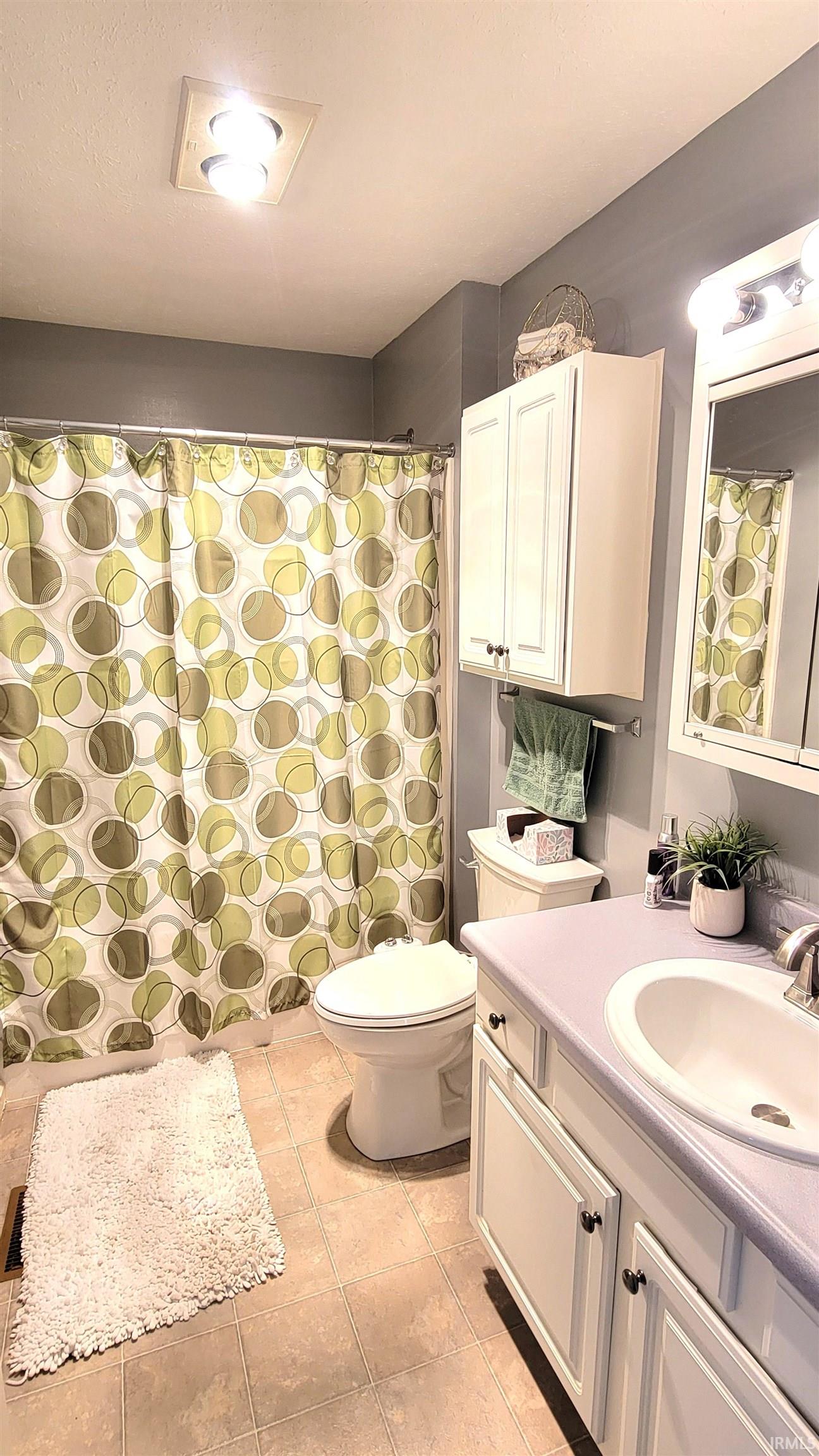 Full bathroom featuring a shower with shower curtain, vanity, and light tile patterned flooring