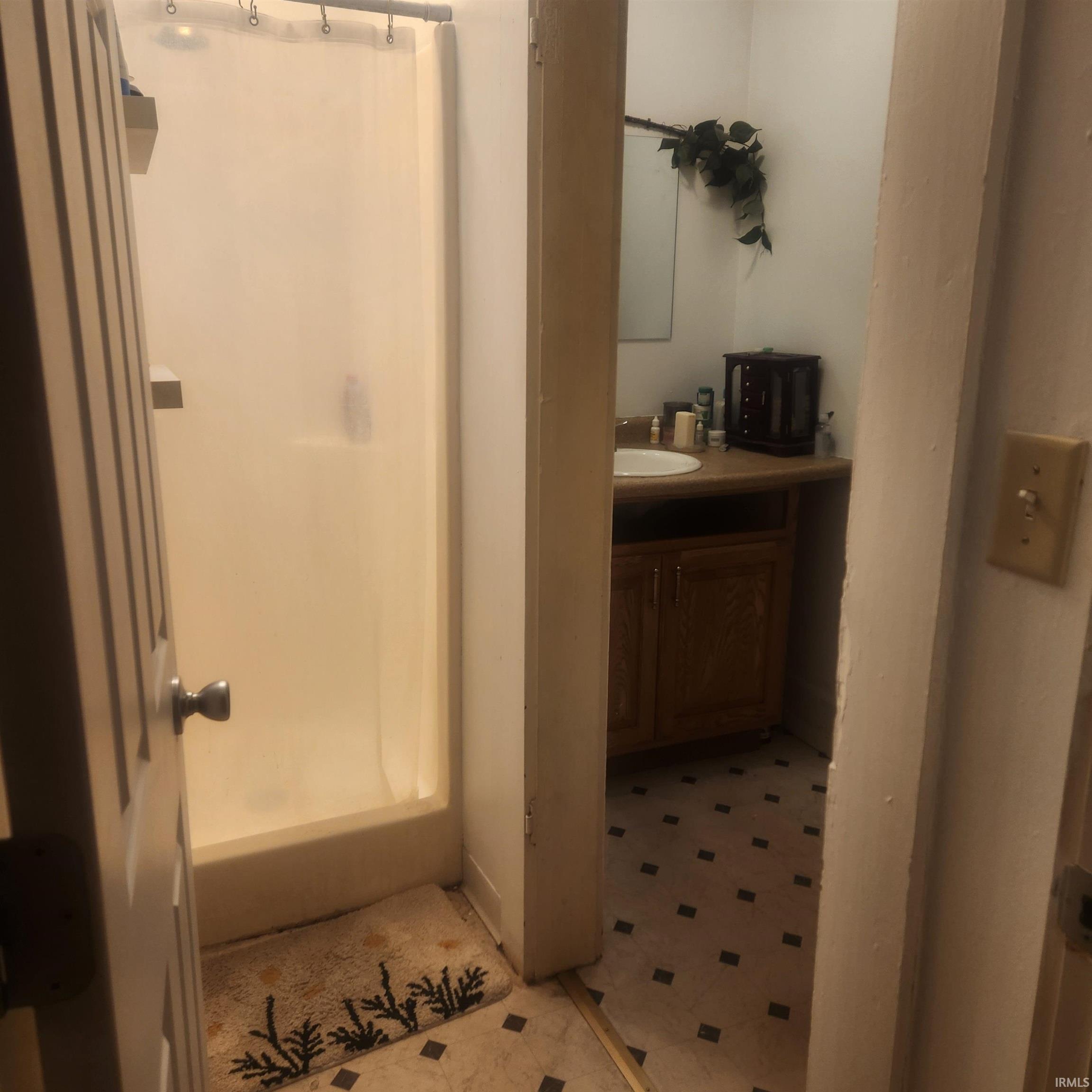 Full bathroom featuring a stall shower, vanity, and light floors