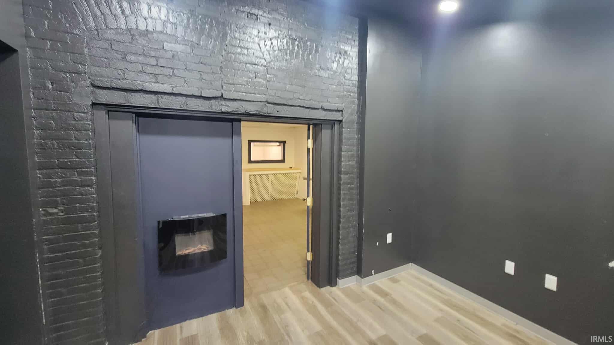 Interior space with a glass covered fireplace and light wood-style flooring