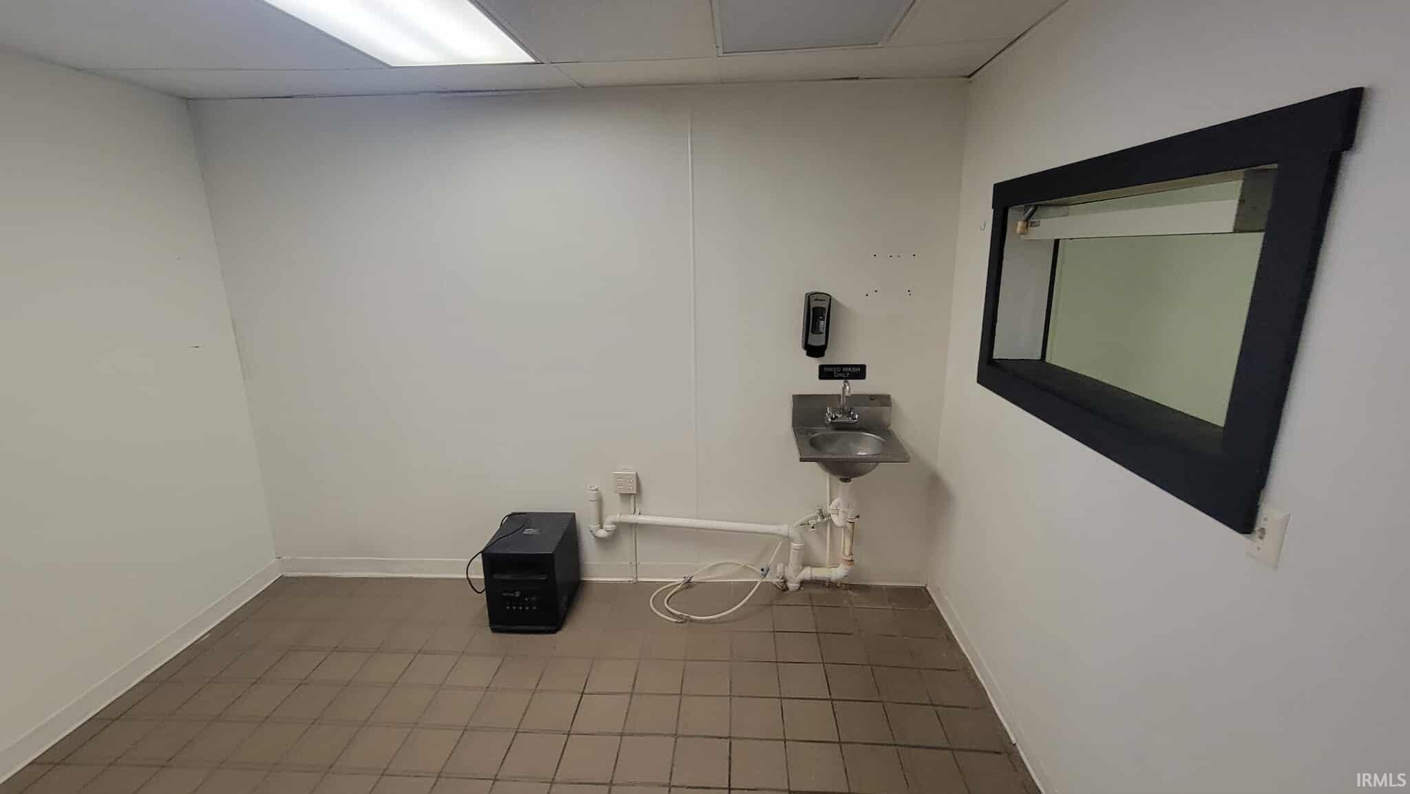 Laundry room featuring a drop ceiling and baseboards