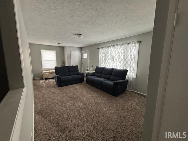 Carpeted living area featuring a textured ceiling and baseboards