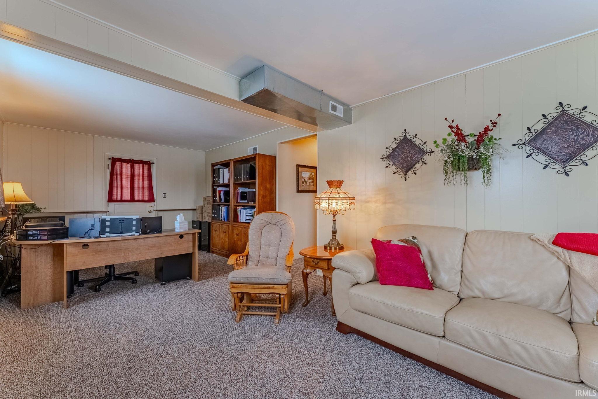 Living room featuring carpet floors, an office area, and wood walls