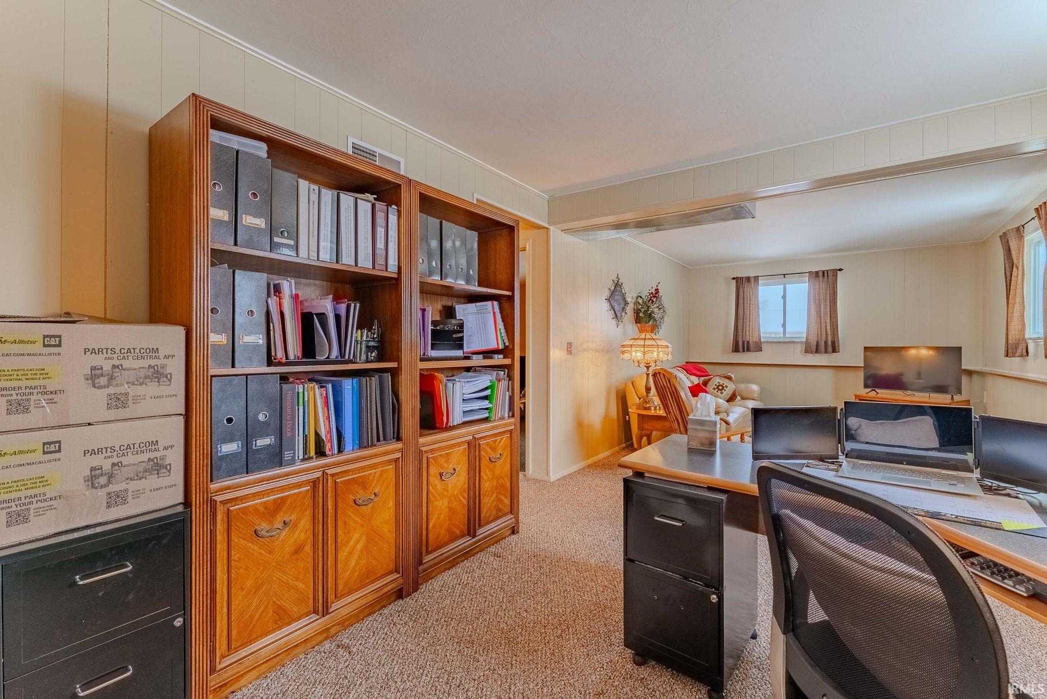 Office featuring light carpet and wood walls