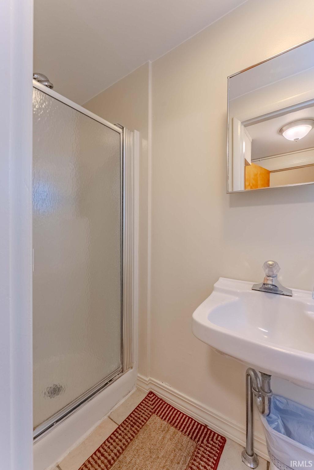 Bathroom with a shower stall and tile patterned floors