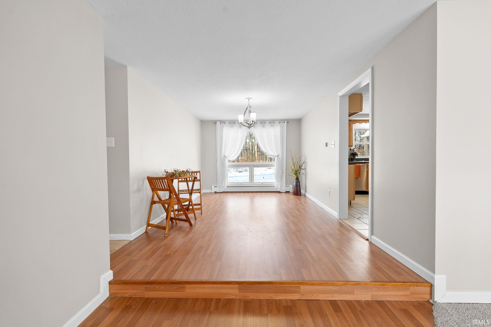 Interior space with a chandelier, light wood finished floors, and baseboard heating