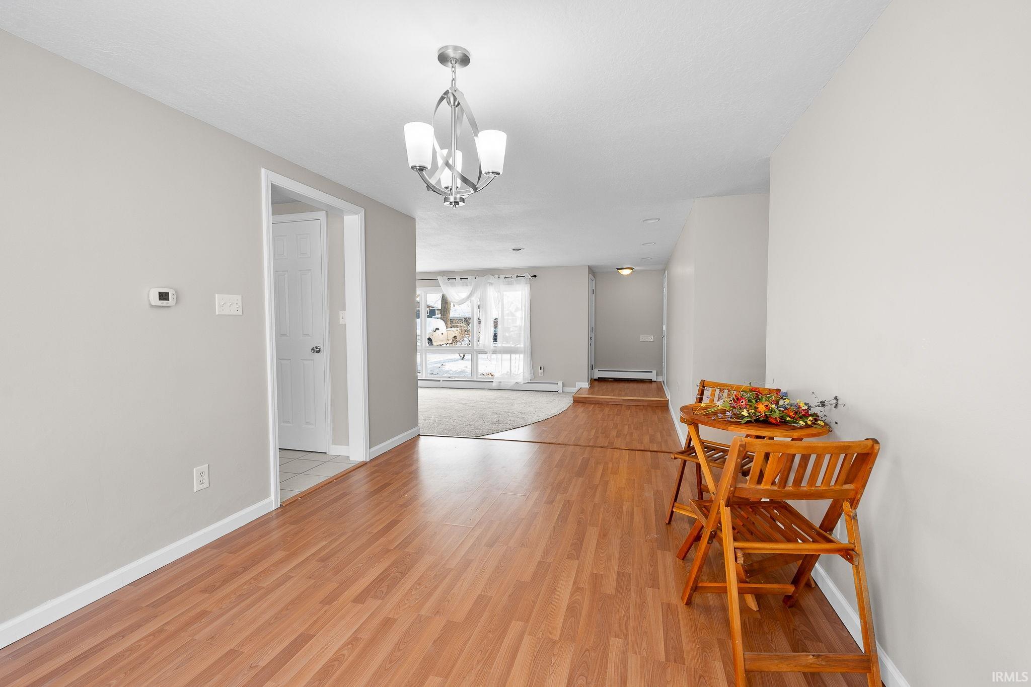 Dining room with light wood-style floors, a chandelier, and a baseboard heating unit