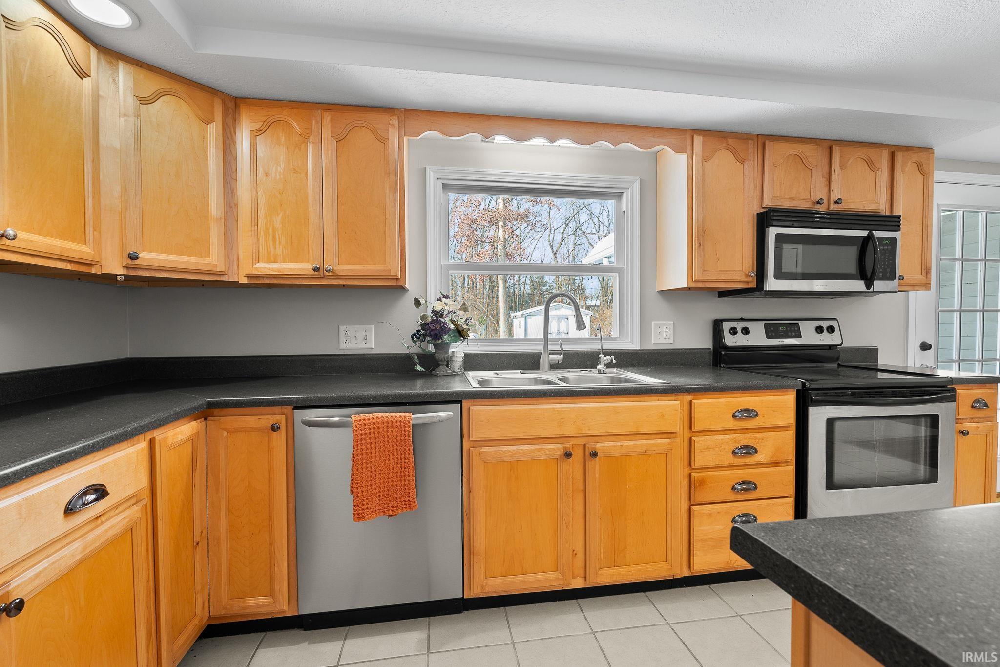 Kitchen with dark countertops, stainless steel appliances, and light tile patterned floors
