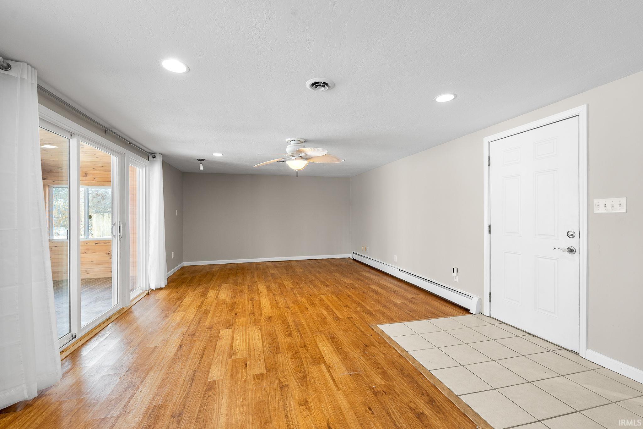 Spare room featuring light wood finished floors, a baseboard radiator, recessed lighting, and ceiling fan