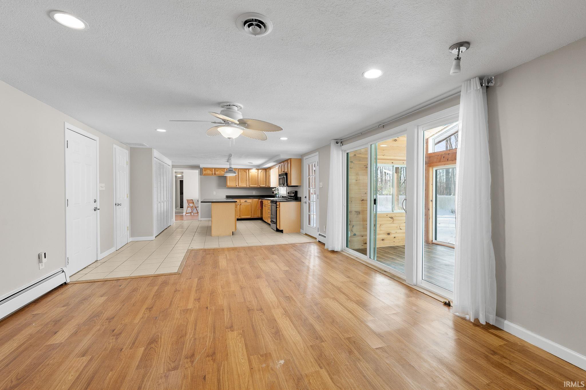 Kitchen with dark countertops, open floor plan, light wood finished floors, recessed lighting, and black electric range
