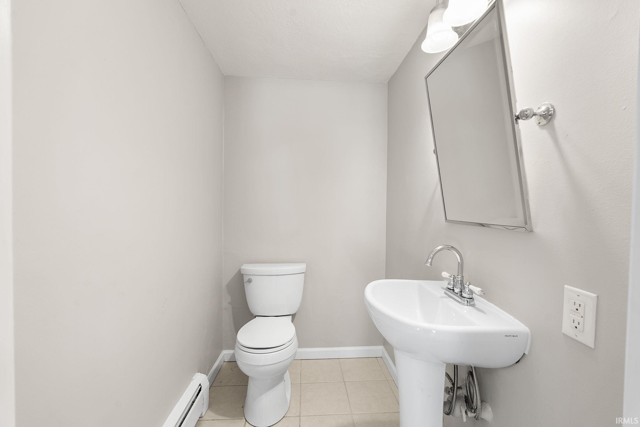 Half bathroom with light tile patterned floors and a baseboard radiator