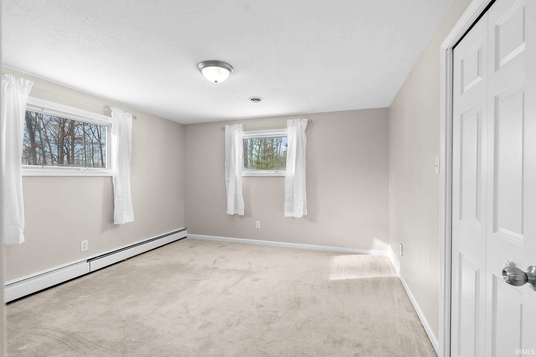 Unfurnished bedroom featuring a baseboard heating unit, carpet flooring, and a closet