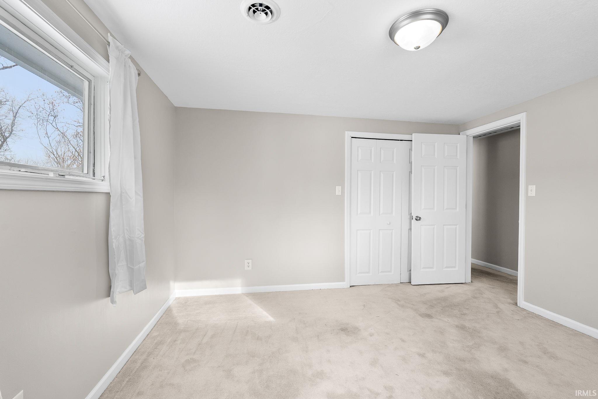 Unfurnished bedroom featuring light colored carpet and a closet