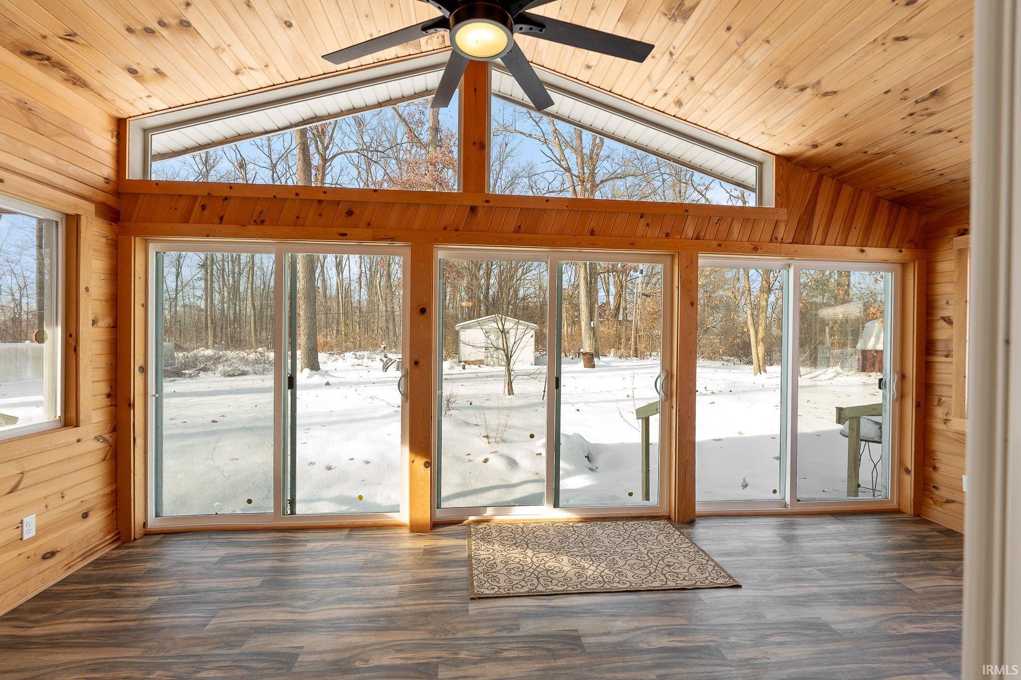 Unfurnished sunroom featuring wooden walls, lofted ceiling, wood finished floors, and wood ceiling