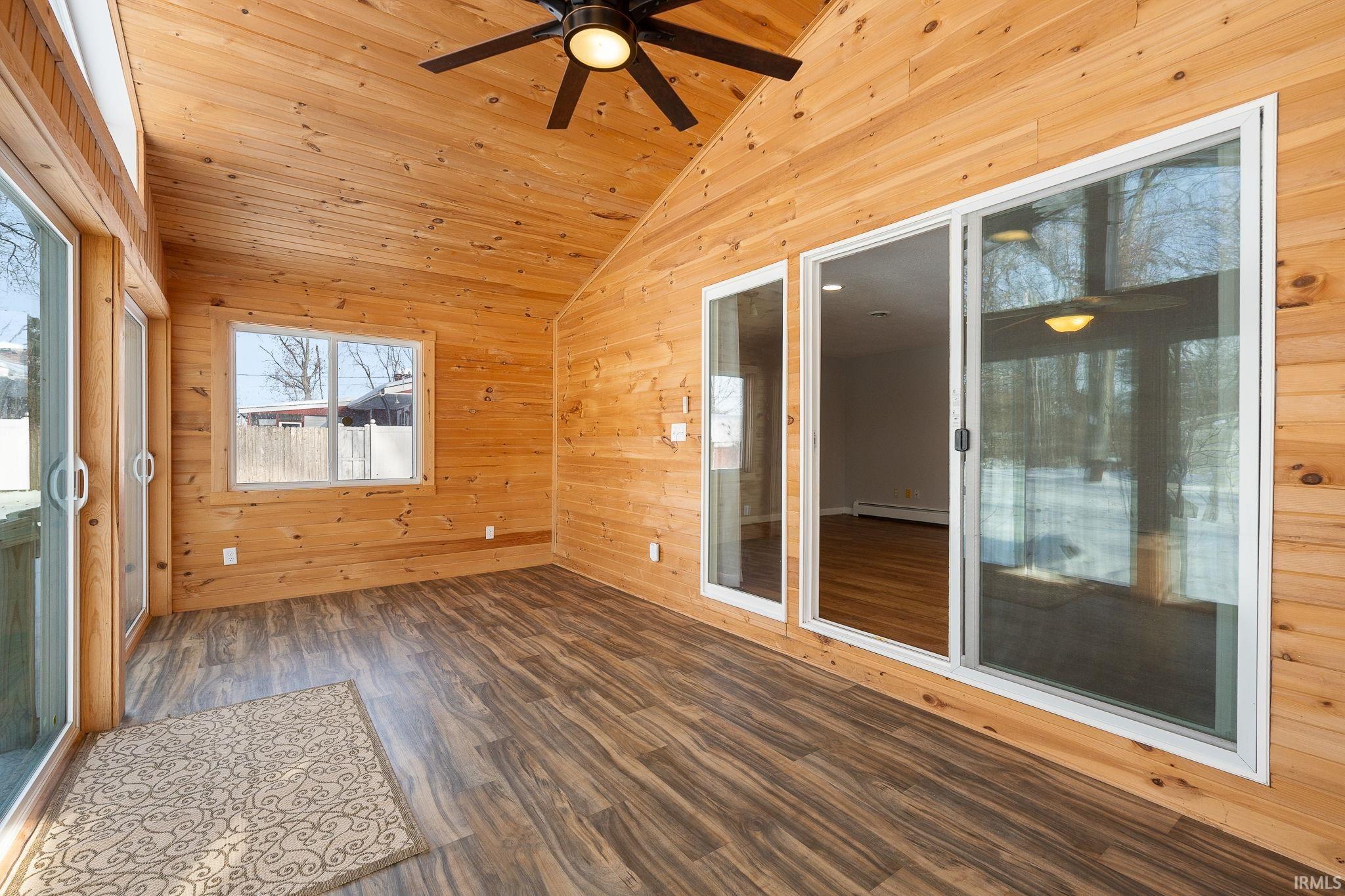 Unfurnished sunroom with vaulted ceiling and a baseboard radiator