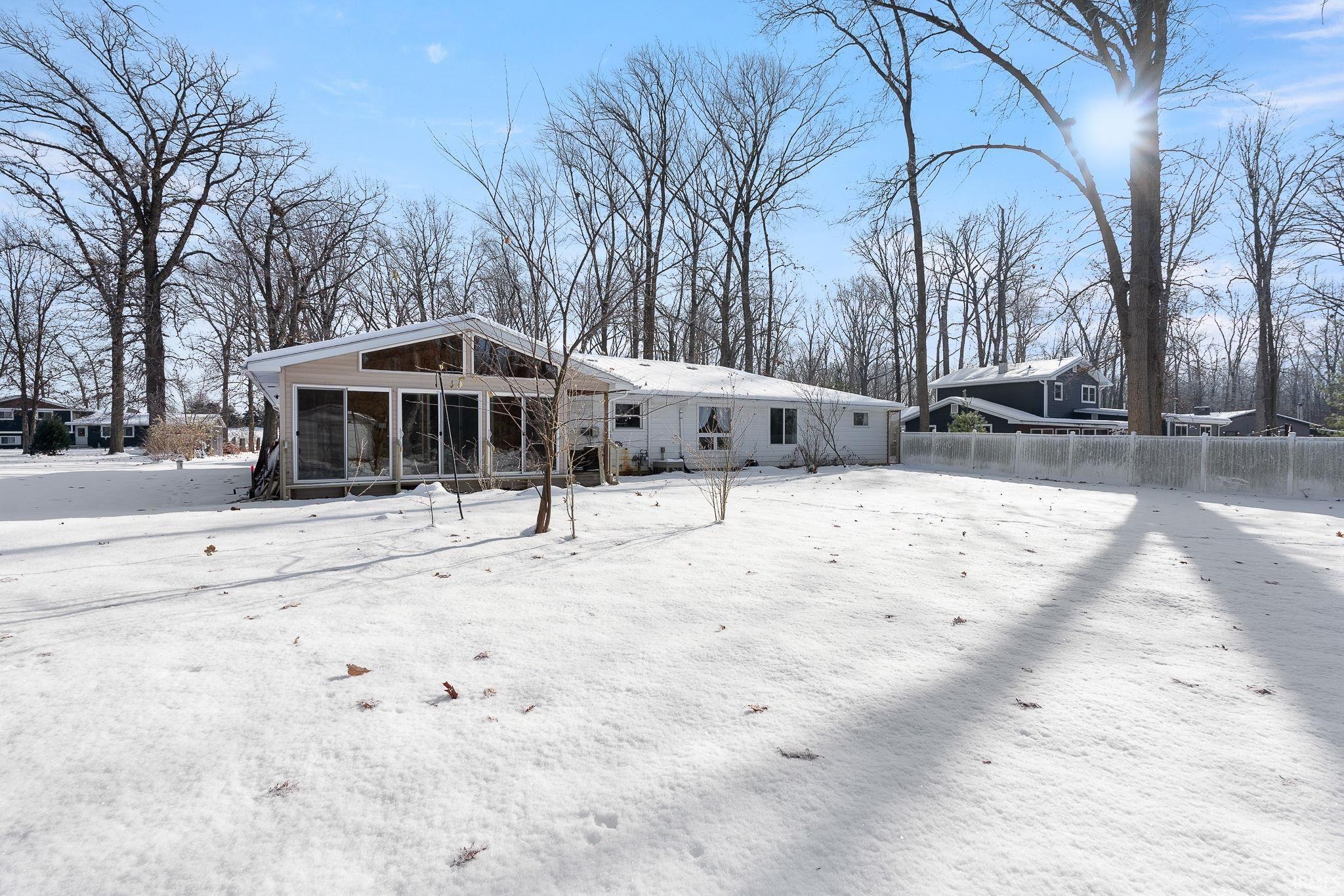 Snow covered rear of property featuring a sunroom