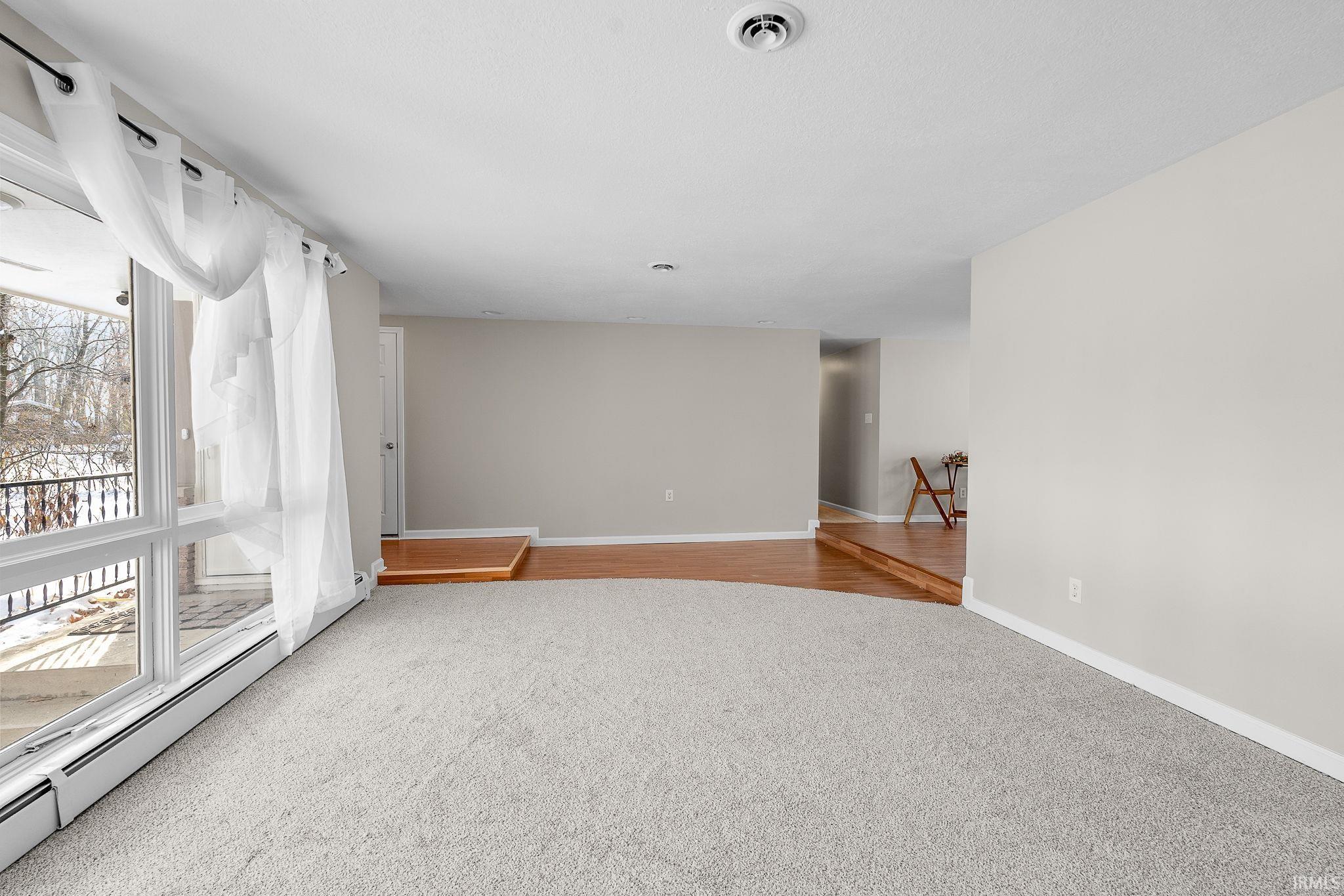 Unfurnished room featuring a baseboard radiator and light carpet