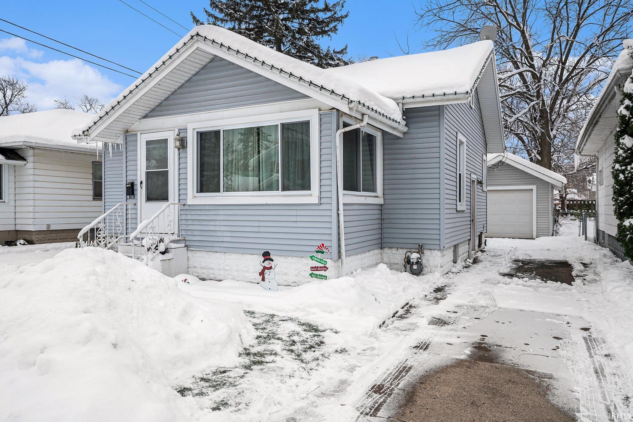 View of front of property featuring a detached garage and an outdoor structure