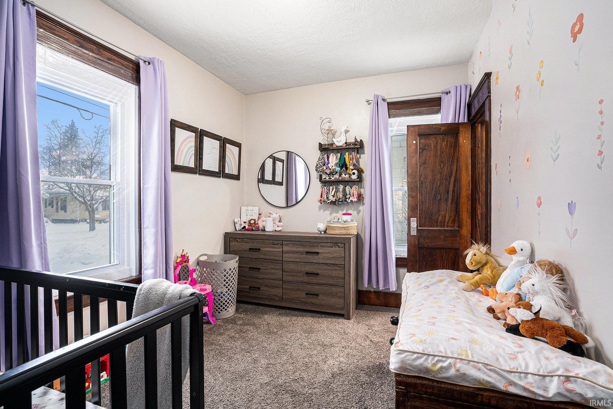 Carpeted bedroom with a nursery area and a textured ceiling