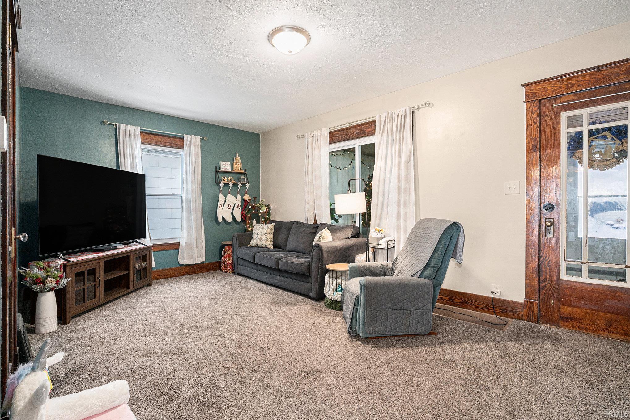 Carpeted living room featuring a textured ceiling and baseboards