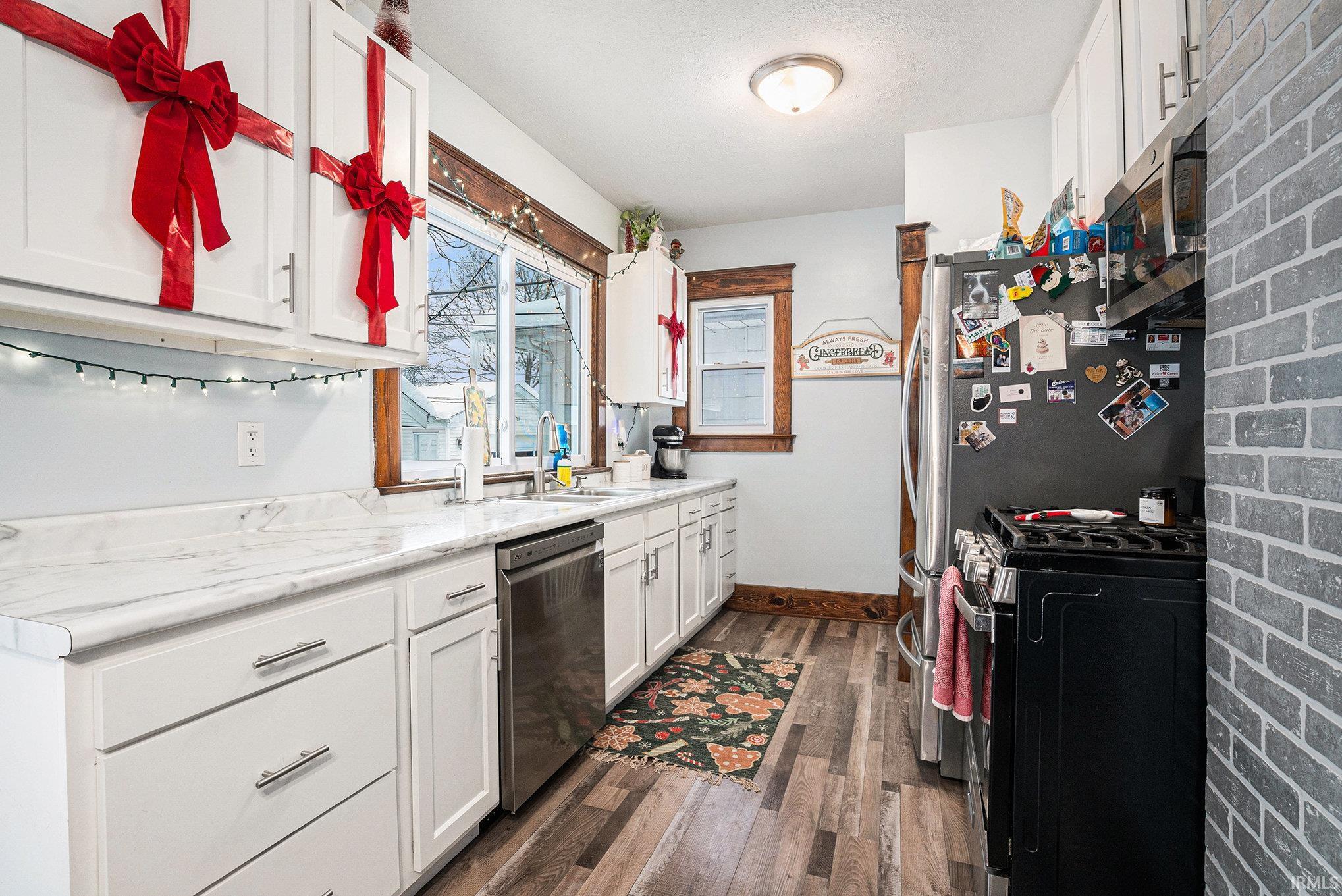 Kitchen featuring white cabinetry, appliances with stainless steel finishes, and dark wood finished floors