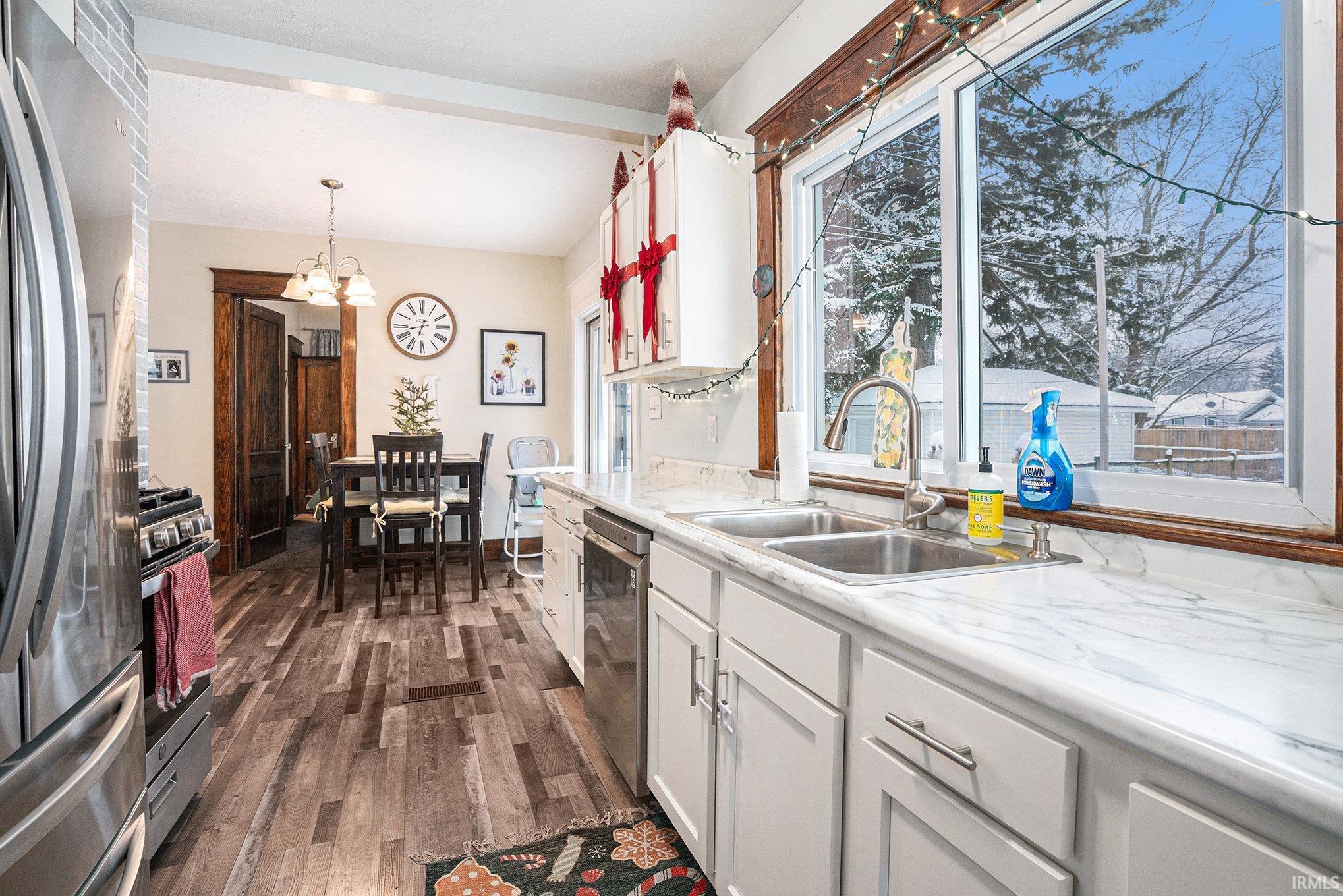 Kitchen featuring light countertops, appliances with stainless steel finishes, white cabinets, and dark wood-style floors