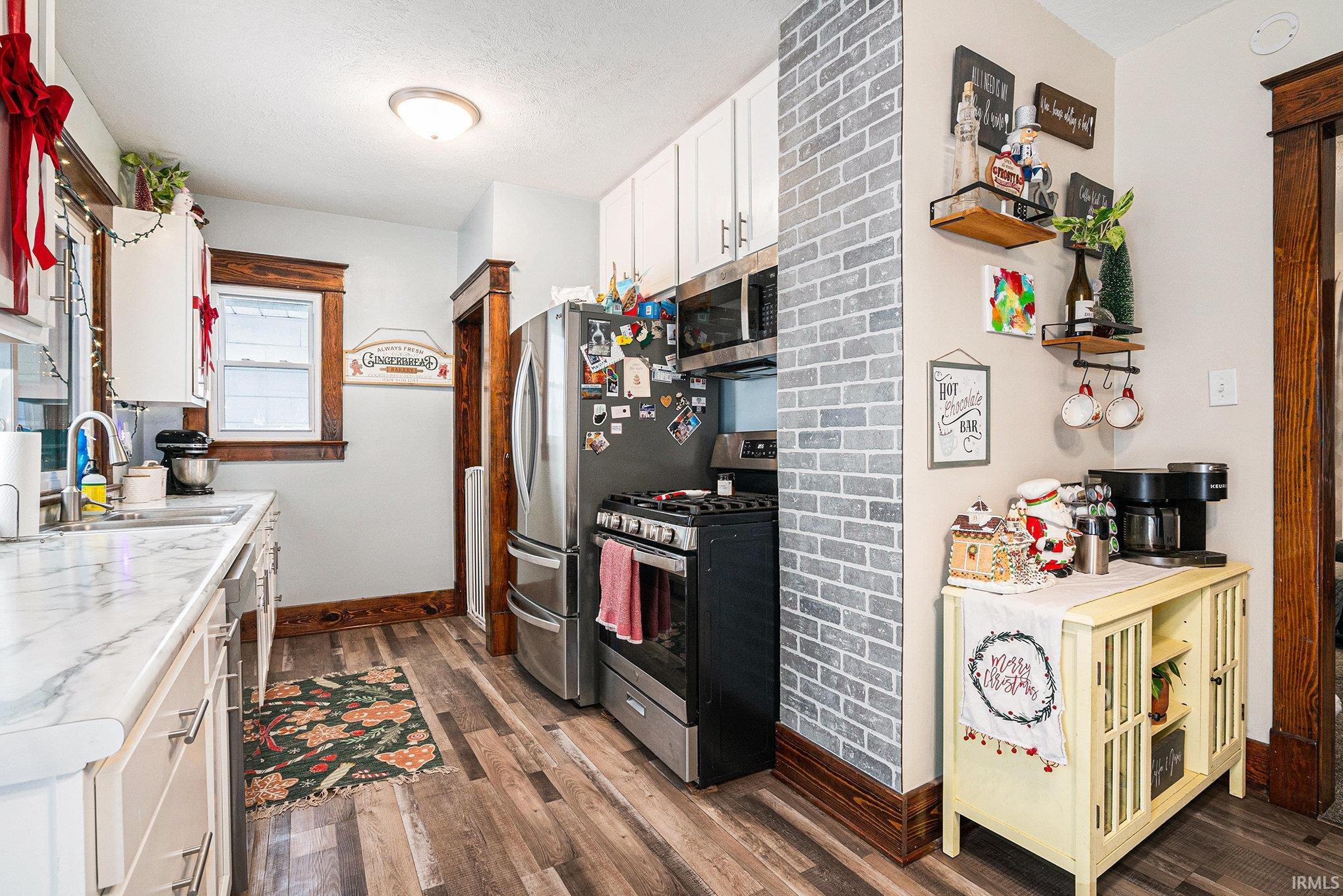 Kitchen with appliances with stainless steel finishes, white cabinets, light countertops, dark wood finished floors, and a textured ceiling