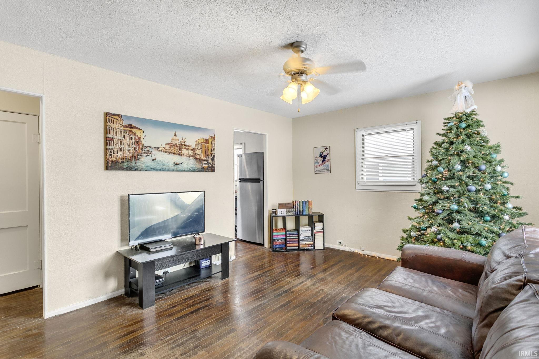 Living area featuring dark wood-style flooring, a textured ceiling, and a ceiling fan