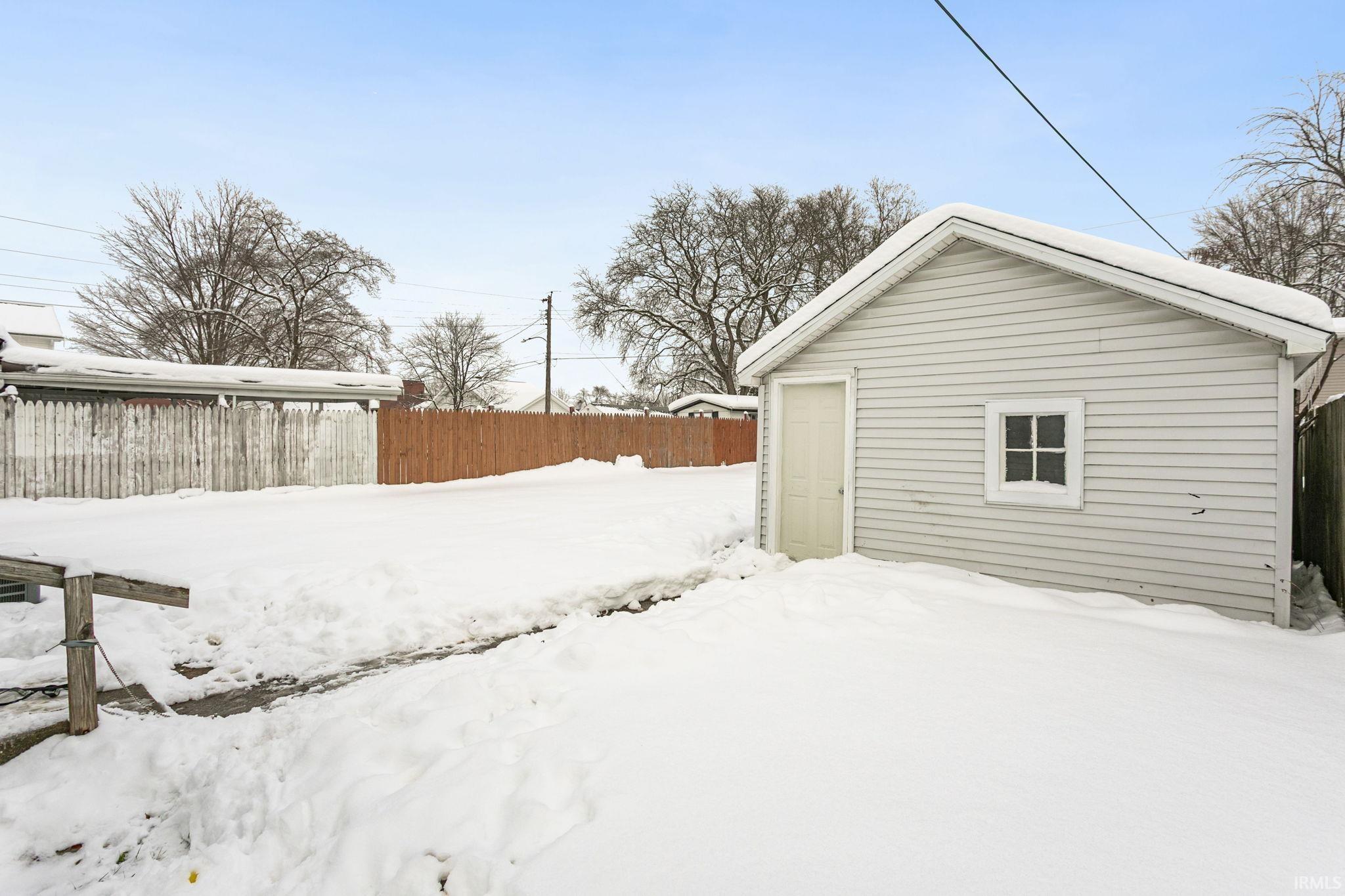 Yard covered in snow featuring an outdoor structure