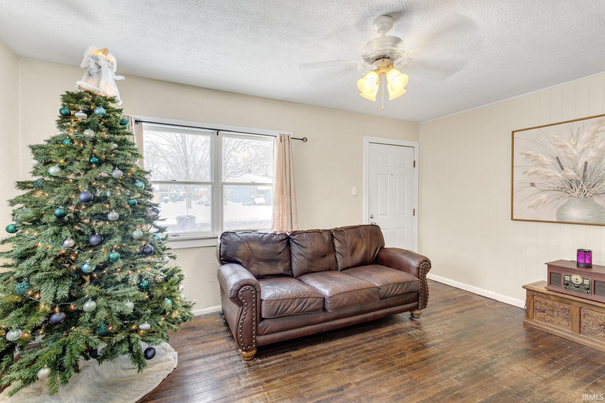 Living area featuring hardwood / wood-style flooring, a ceiling fan, and a textured ceiling