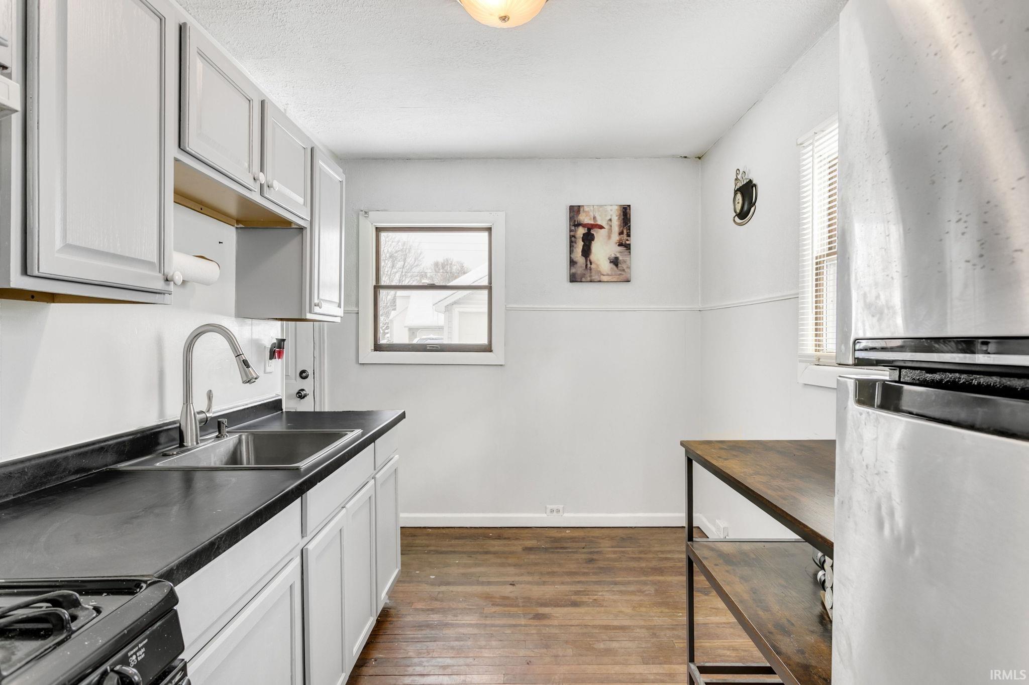 Kitchen featuring freestanding refrigerator, dark countertops, healthy amount of natural light, and dark wood-style flooring
