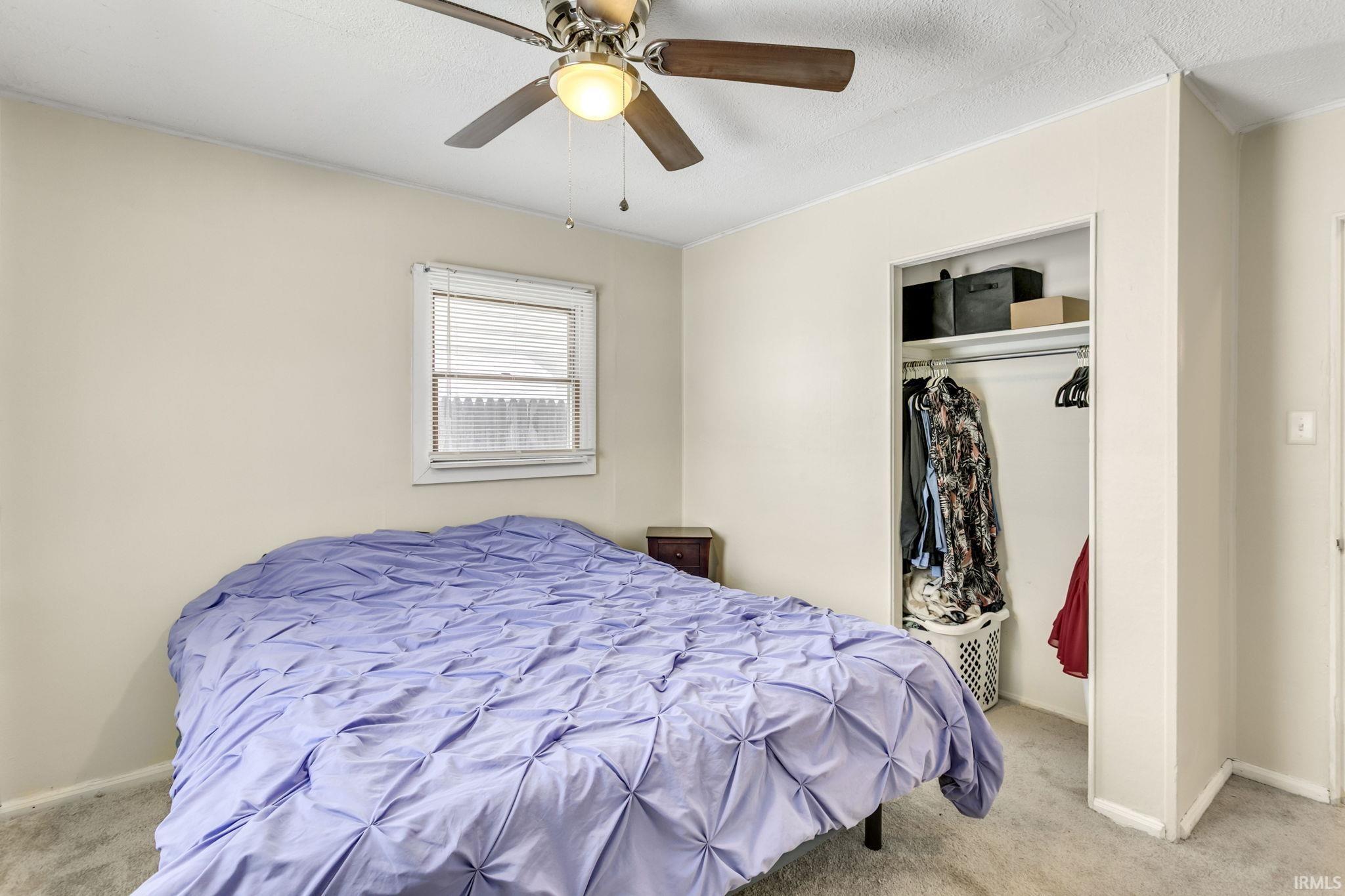 Carpeted bedroom featuring a closet, ceiling fan, and a textured ceiling