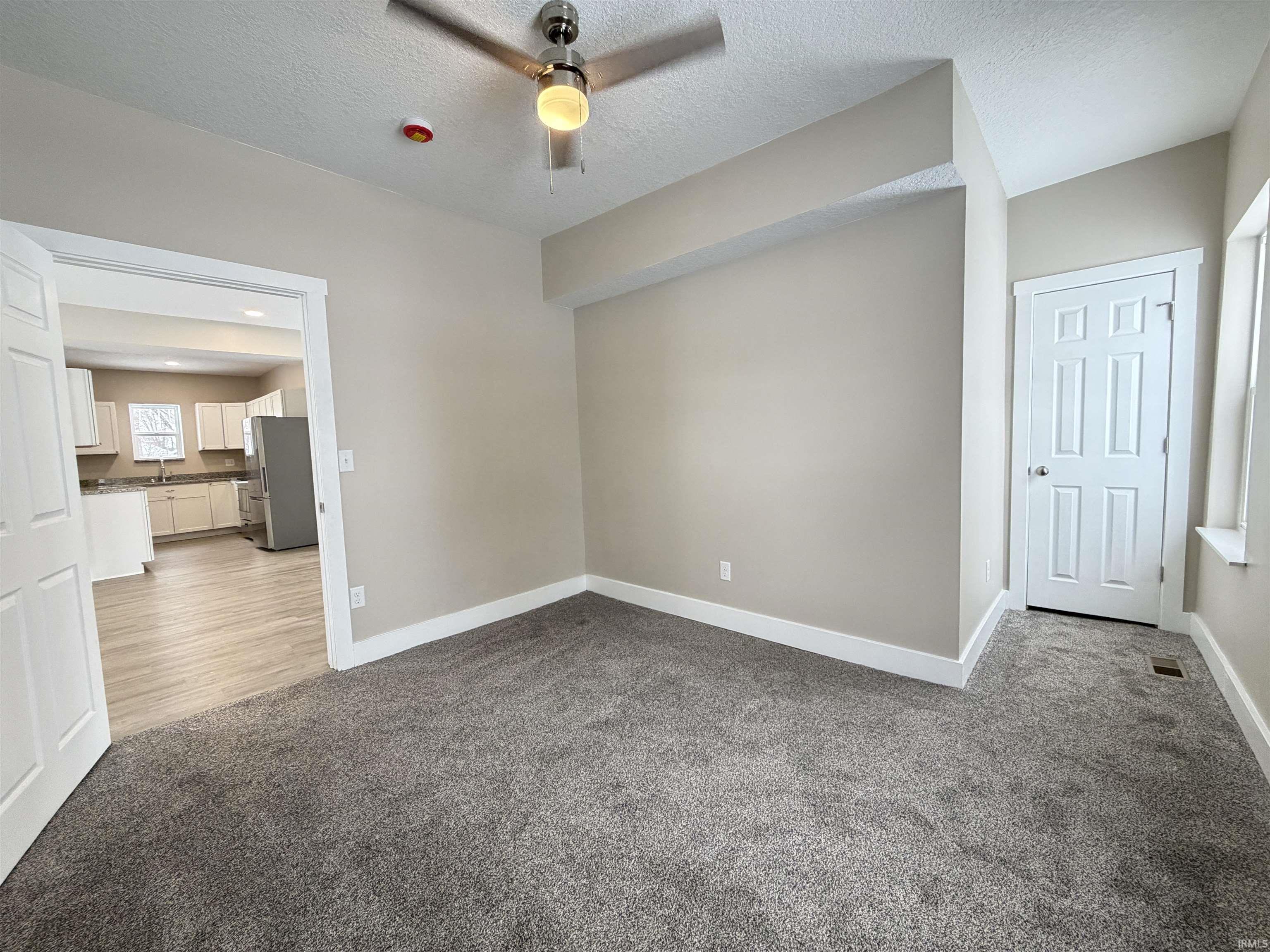 Spare room featuring light colored carpet, a textured ceiling, and ceiling fan