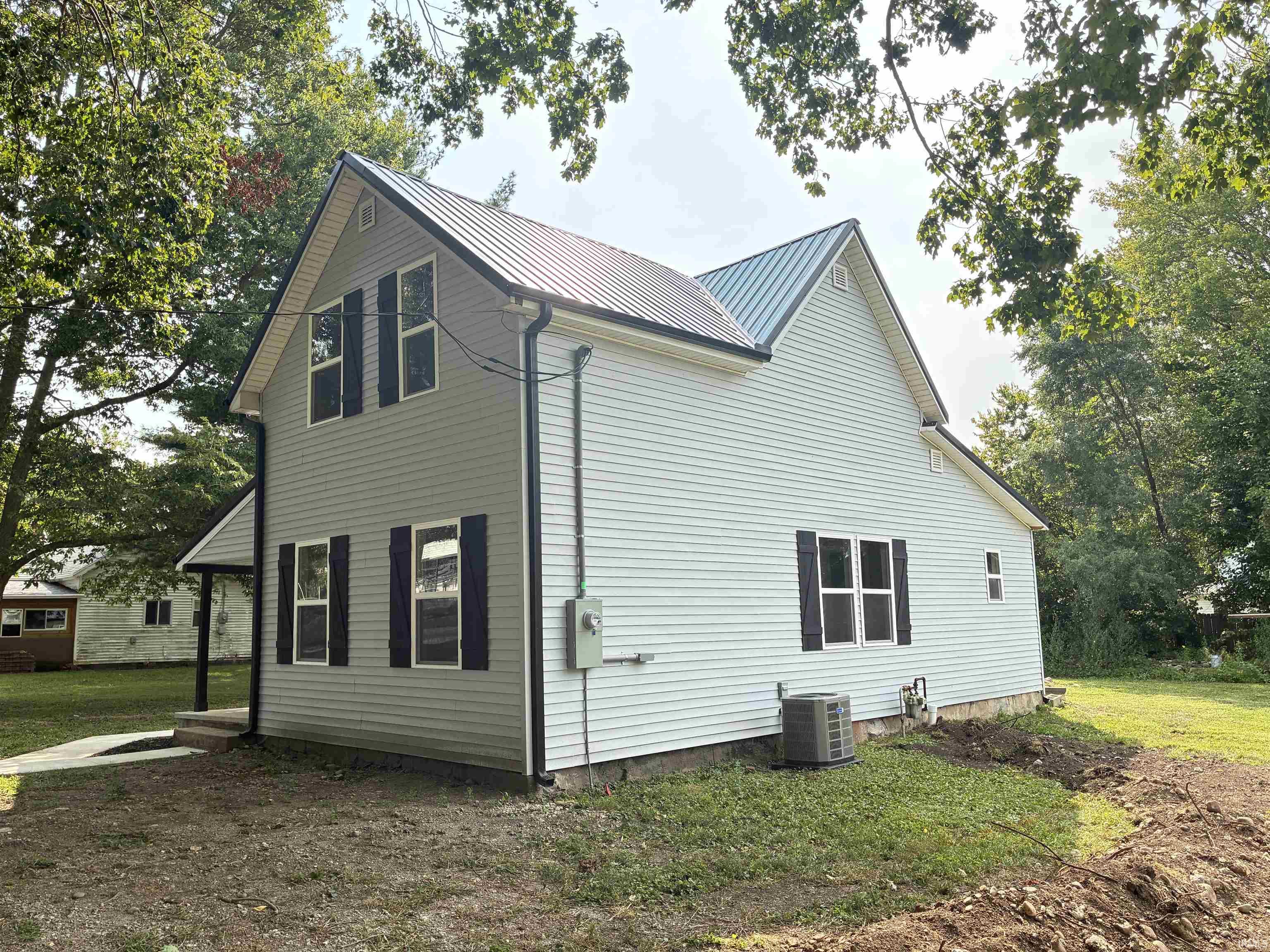 View of side of home with a metal roof and a yard