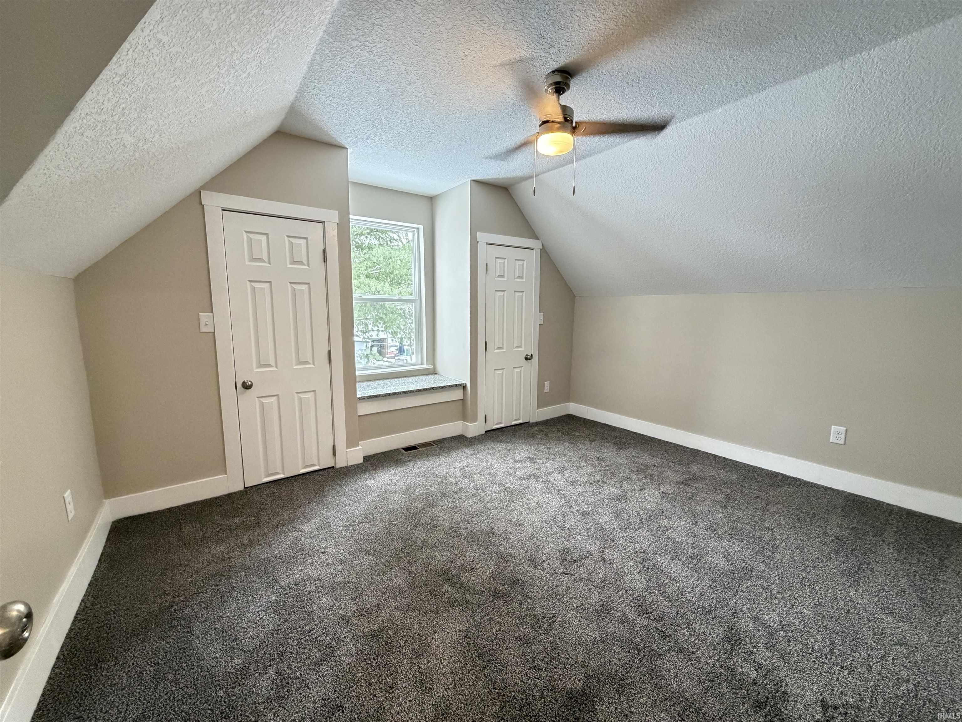 Additional living space featuring lofted ceiling, a textured ceiling, dark carpet, and ceiling fan