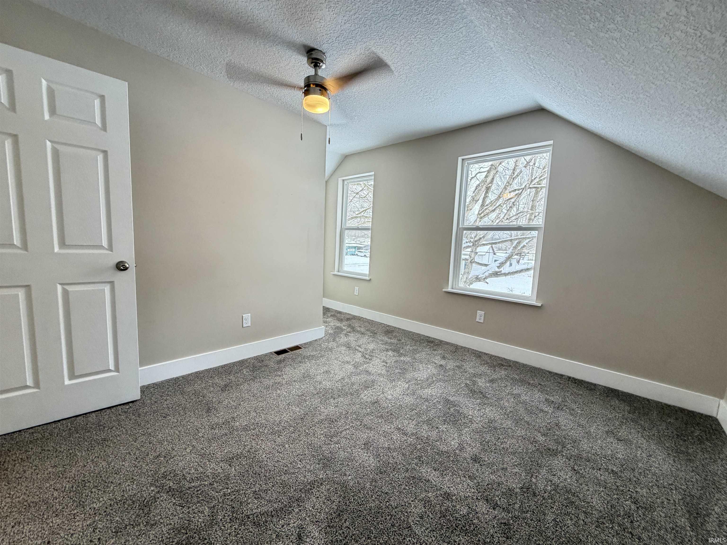 Unfurnished bedroom featuring a textured ceiling, carpet, lofted ceiling, and ceiling fan