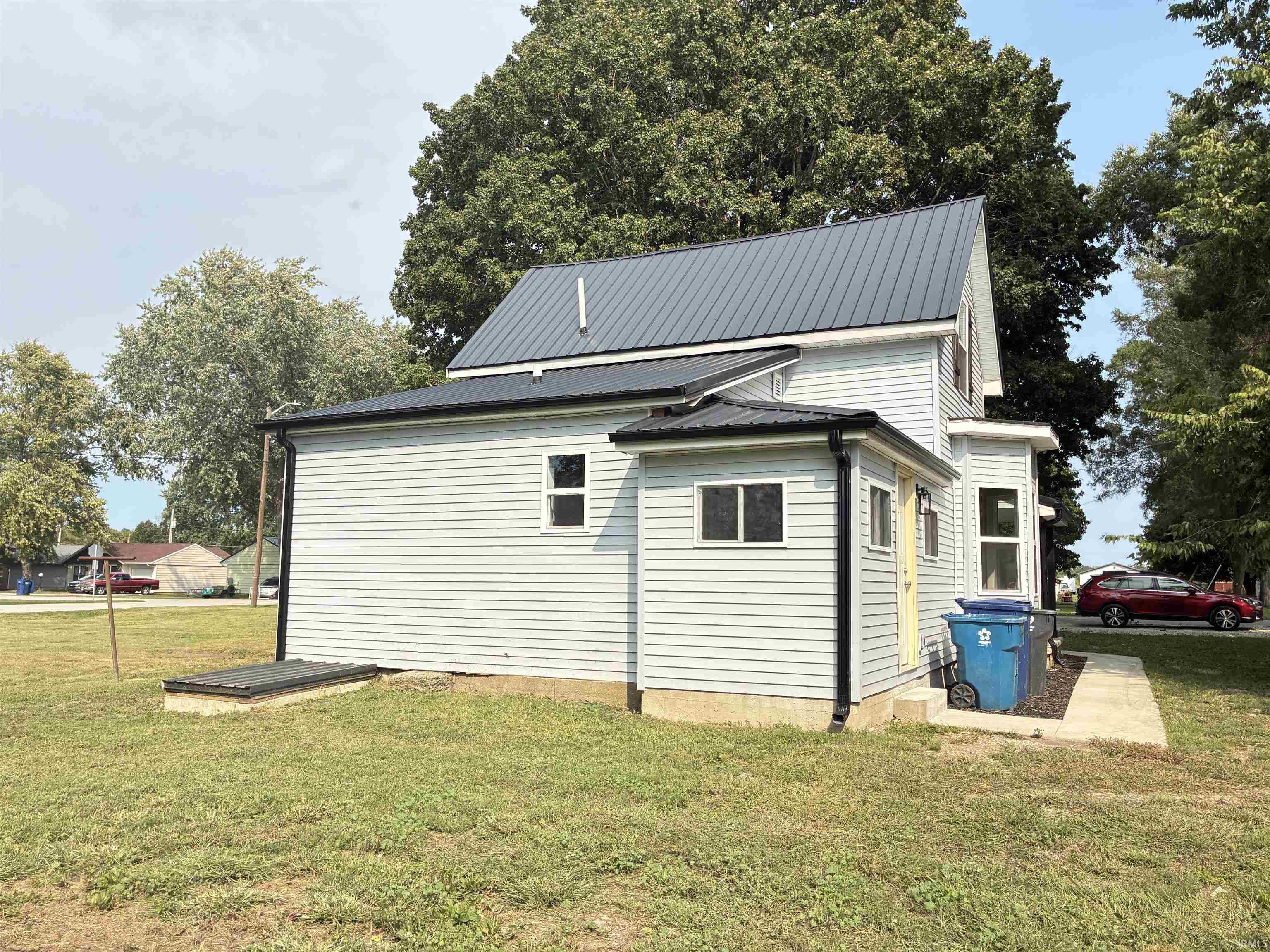 View of side of home with a yard and a metal roof