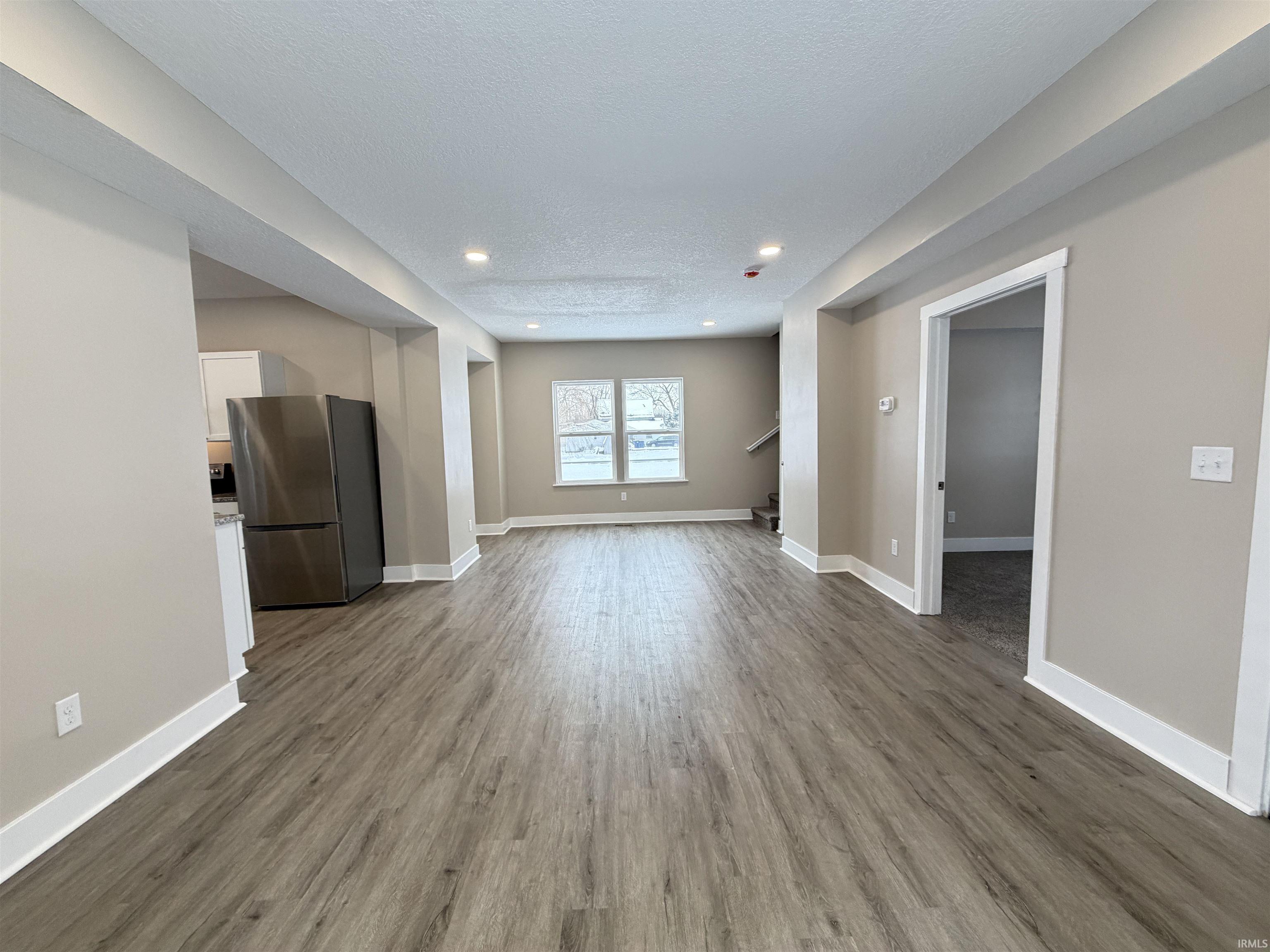 Unfurnished living room with dark wood-style flooring, a textured ceiling, and recessed lighting