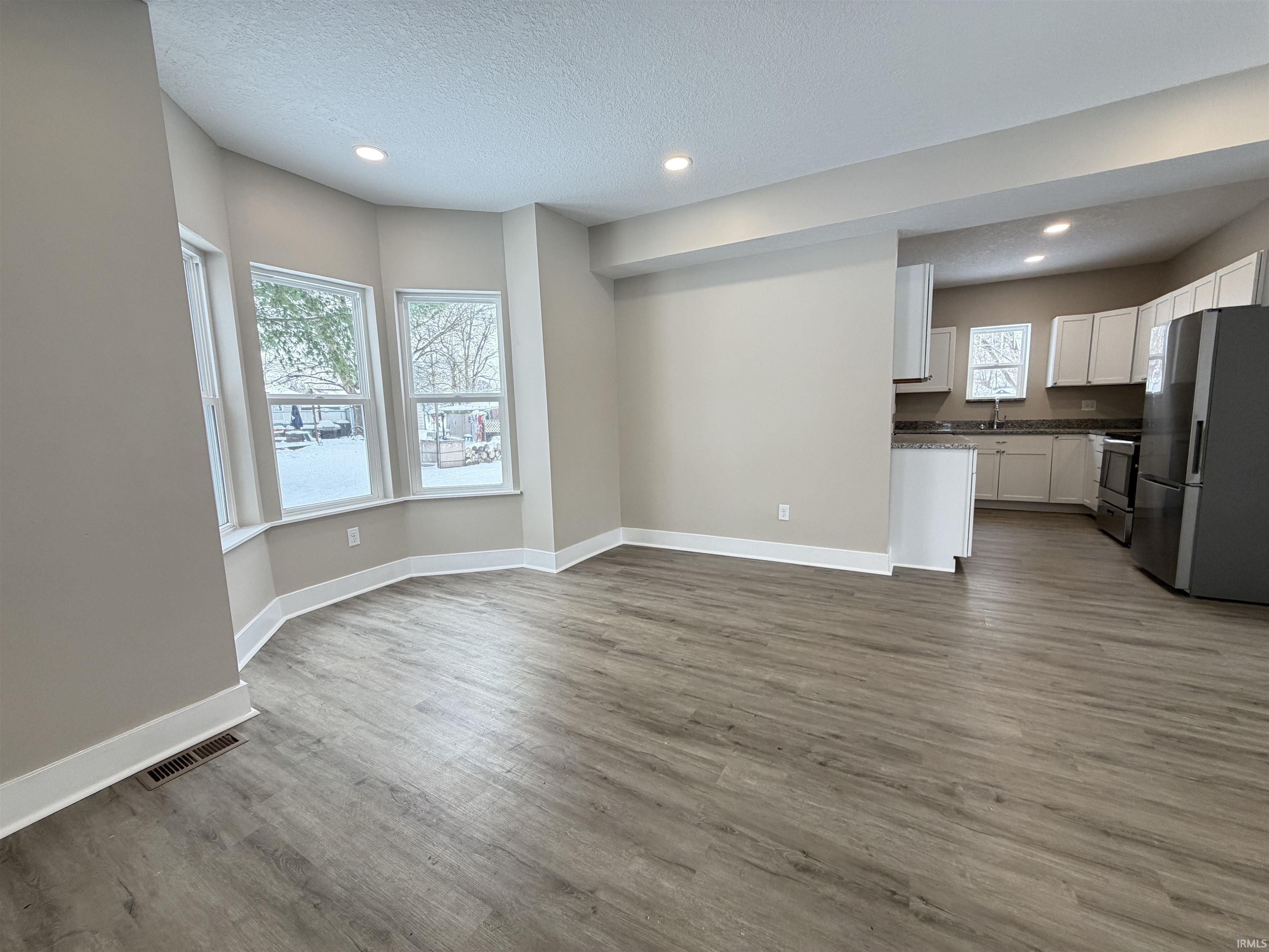 Unfurnished living room with a textured ceiling, dark wood-type flooring, and recessed lighting