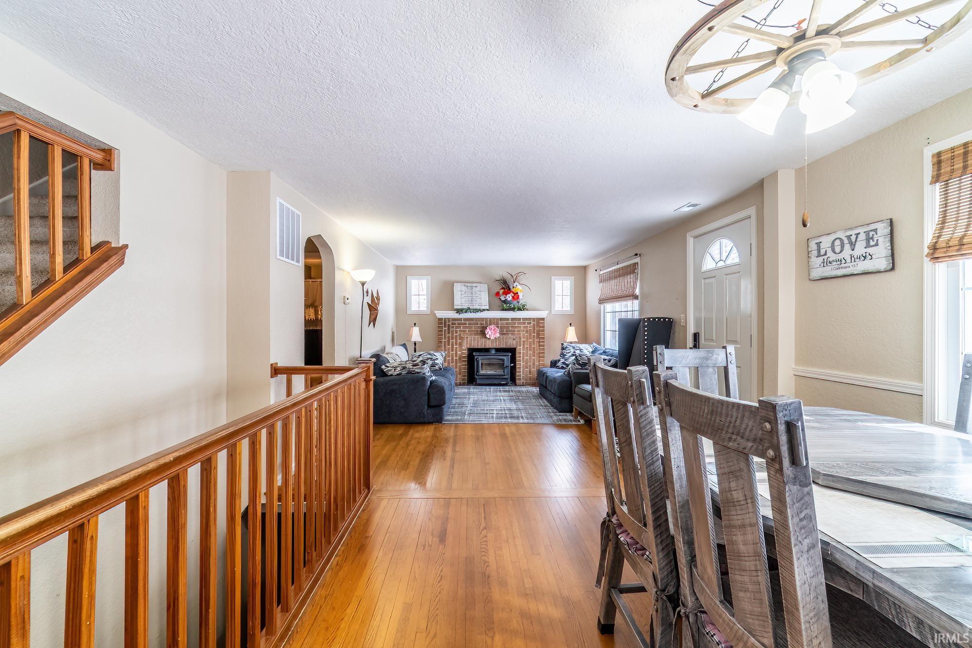 Dining space with a brick fireplace, a ceiling fan, wood-type flooring, and a textured ceiling
