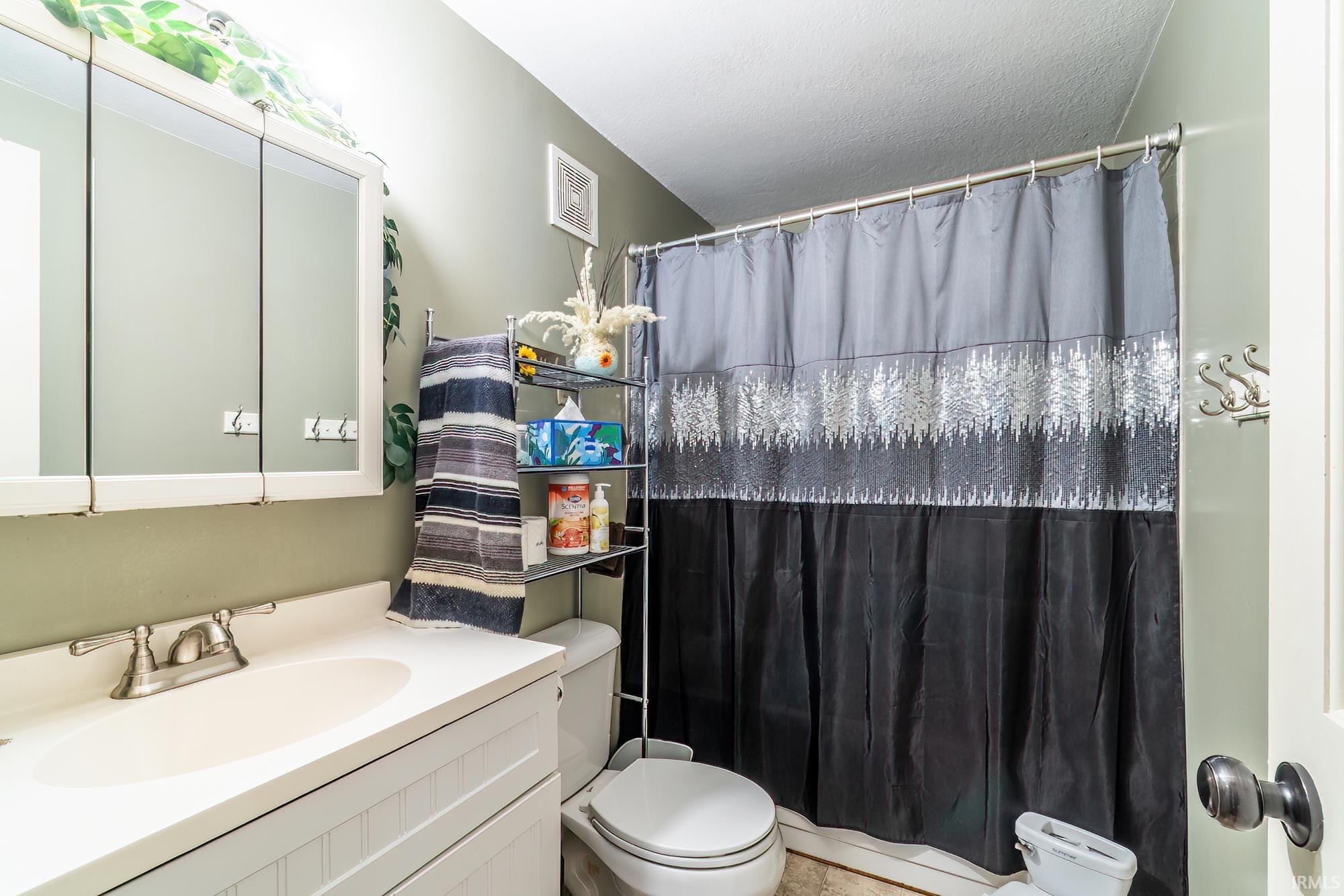 Full bath with a shower with curtain and vanity