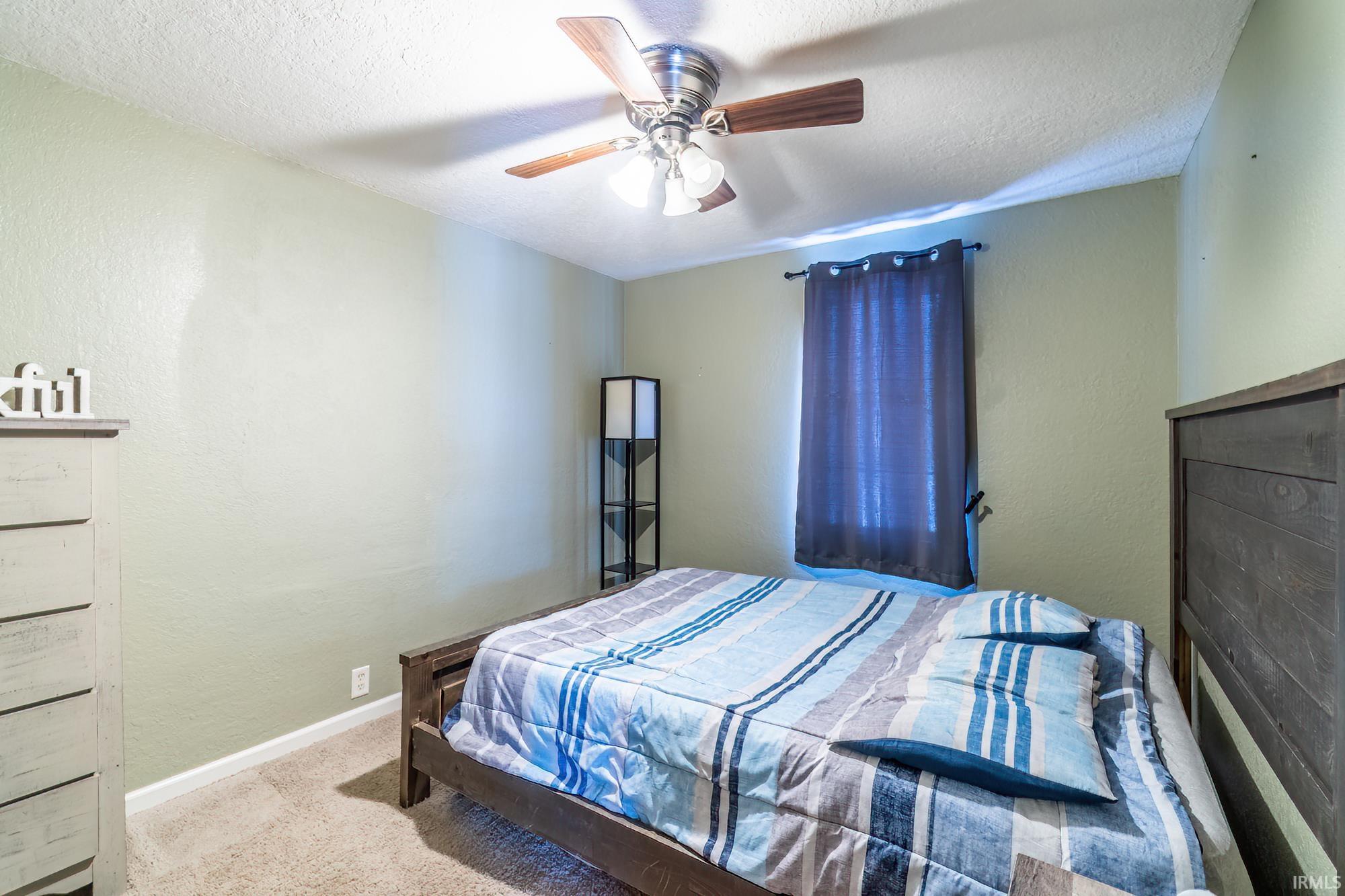 Bedroom featuring carpet flooring, a ceiling fan, a textured wall, and a textured ceiling