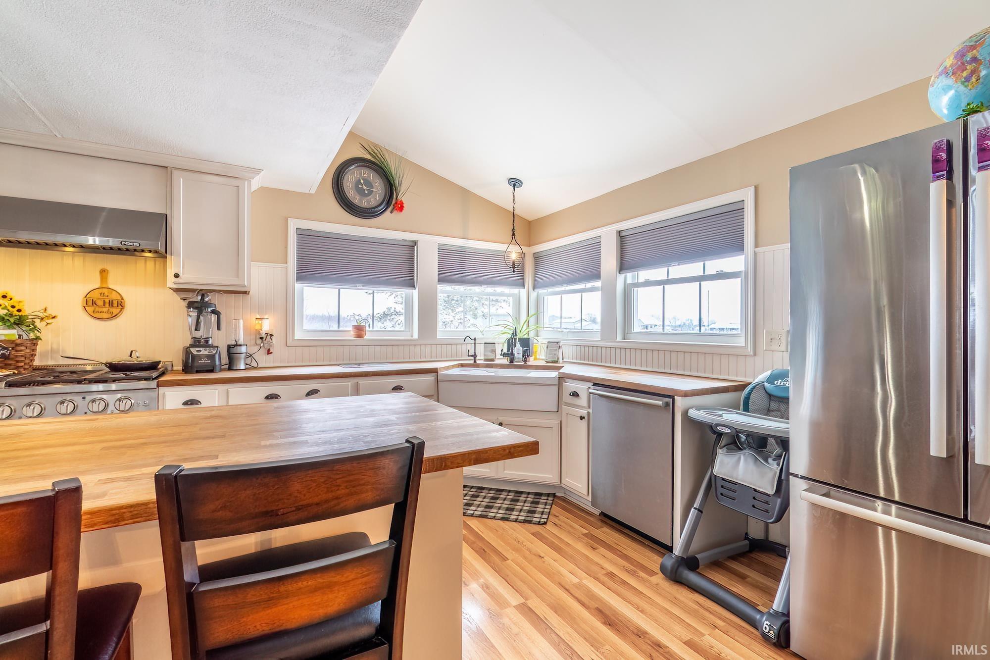 Kitchen featuring wood counters, hanging light fixtures, appliances with stainless steel finishes, healthy amount of natural light, and lofted ceiling