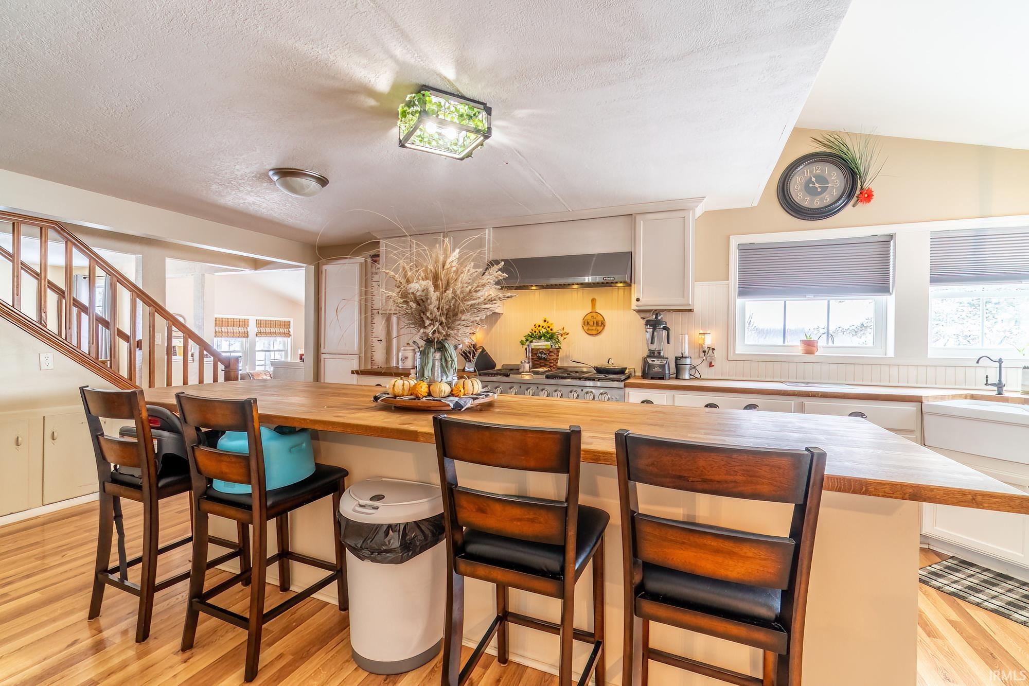 Kitchen with a kitchen bar, light wood-style floors, a kitchen island, butcher block counters, and a textured ceiling