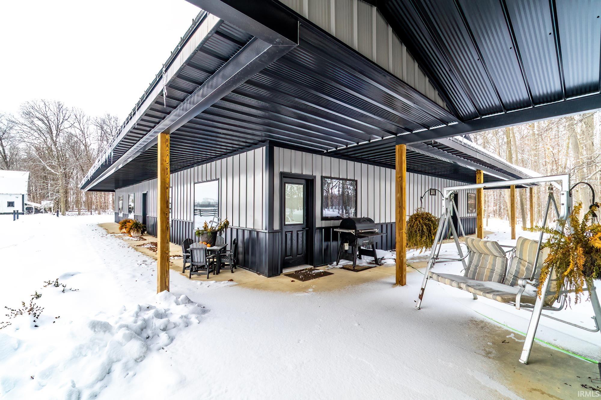 View of snowy exterior featuring a patio area and board and batten siding