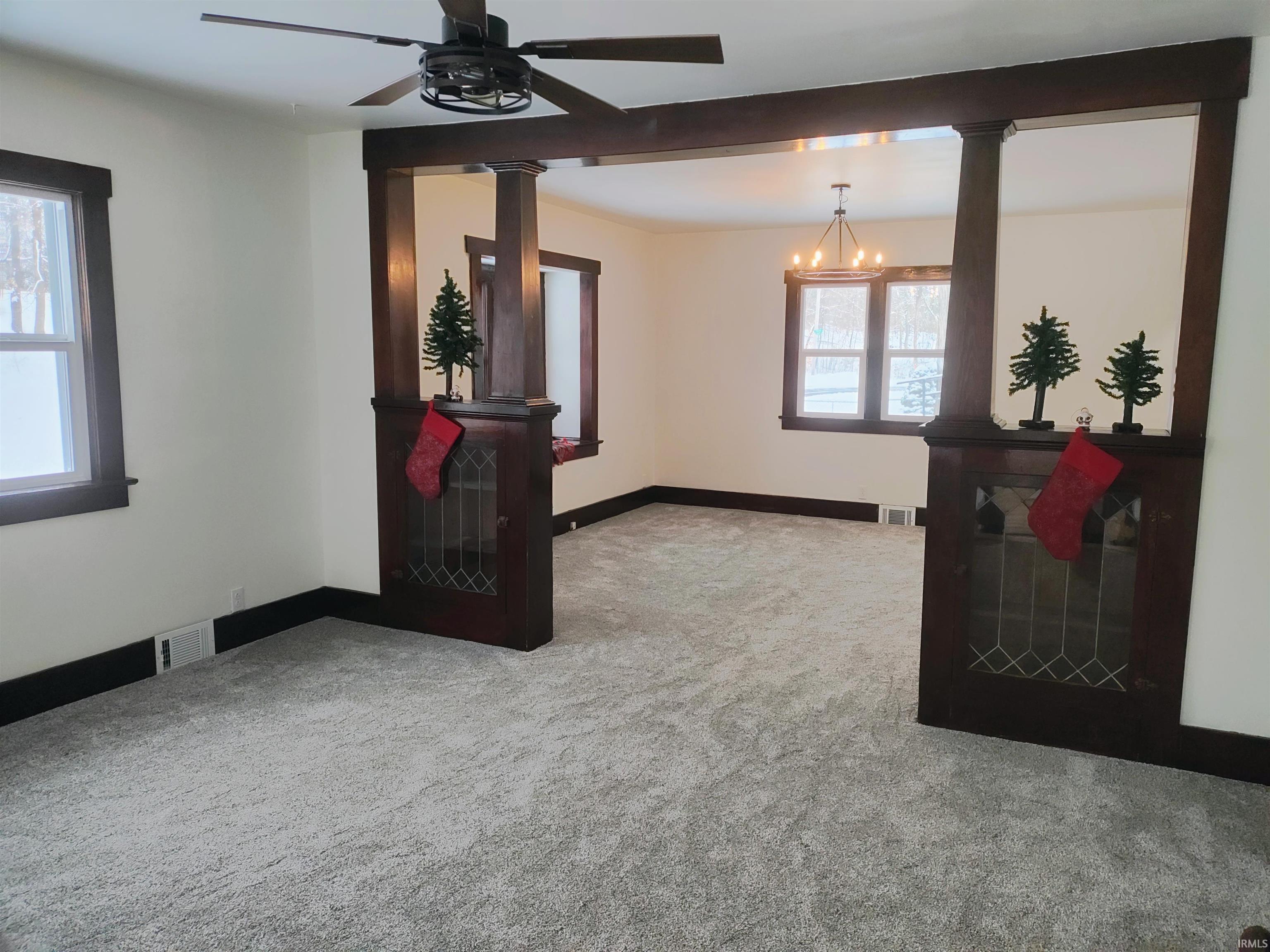 Carpeted spare room featuring ceiling fan and a chandelier