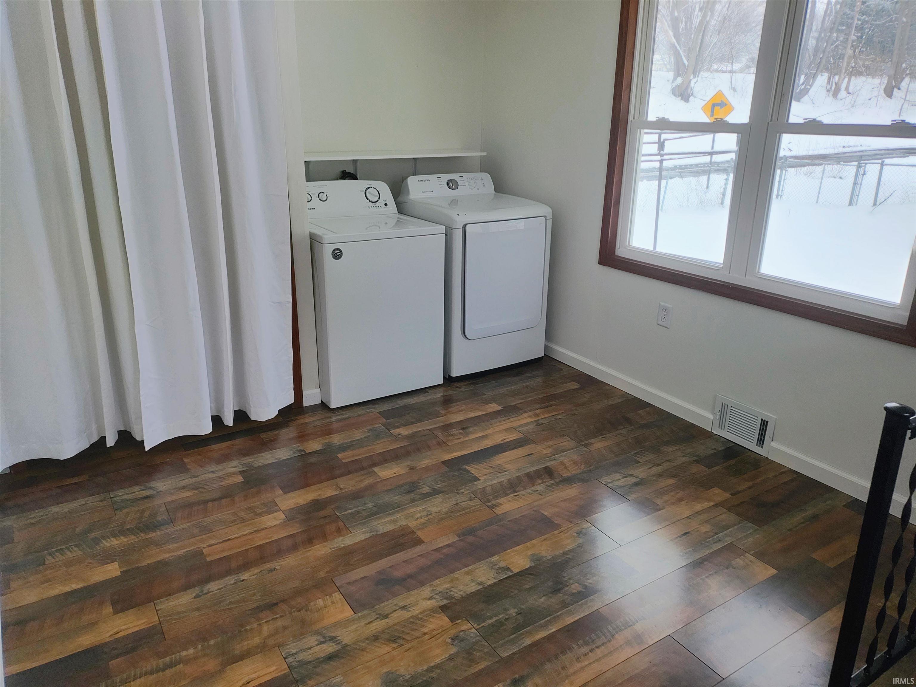 Washroom with dark wood finished floors and washing machine and dryer