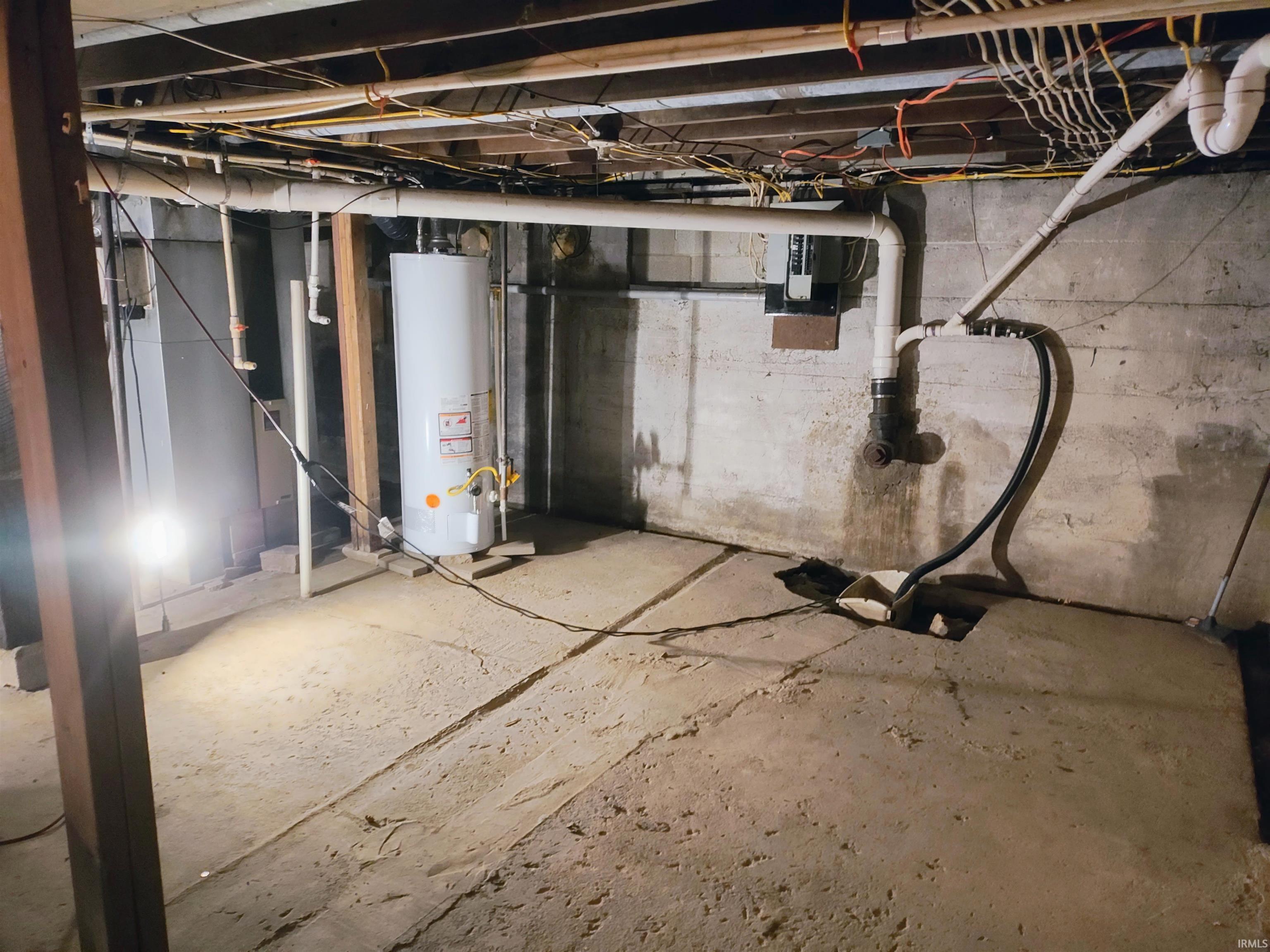 Unfinished below grade area with water heater and electric panel