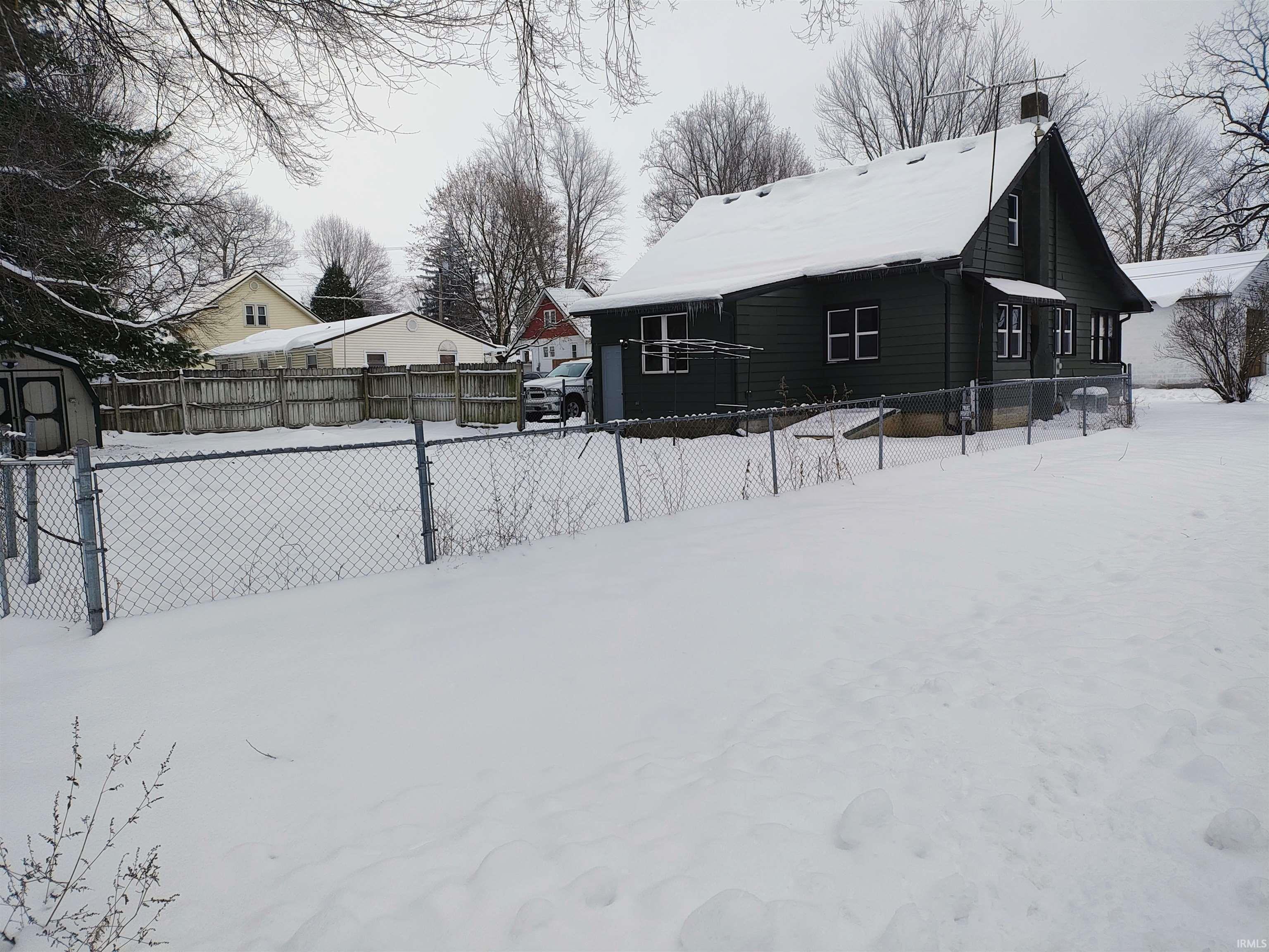 Snow covered property featuring a fenced backyard and a chimney